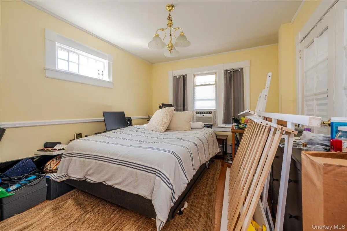 Bedroom with ornamental molding, wood finished floors, and a chandelier Bedroom with ornamental molding, wood finished floors, and a chandelier