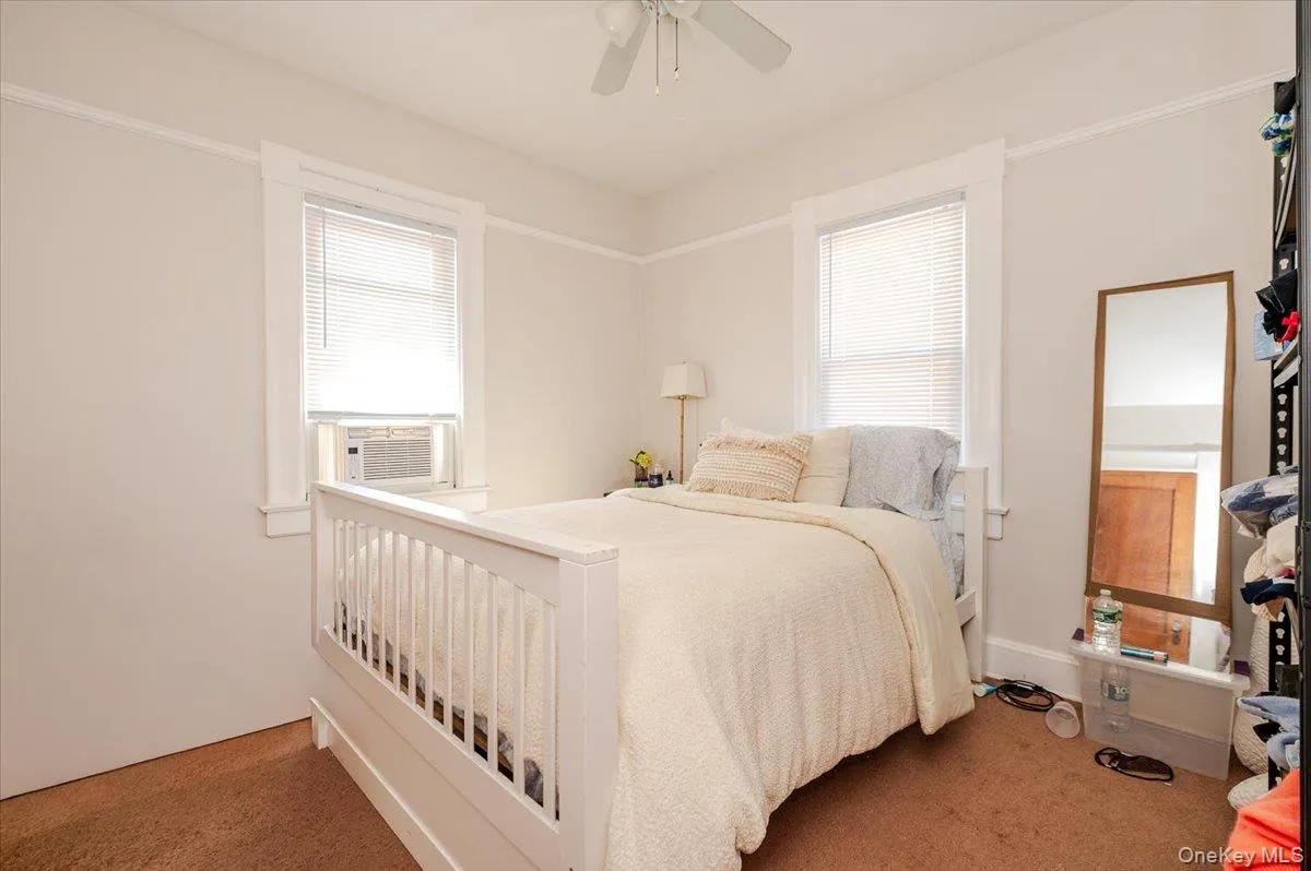 Carpeted bedroom featuring multiple windows, a ceiling fan, and cooling unit Carpeted bedroom featuring multiple windows, a ceiling fan, and cooling unit