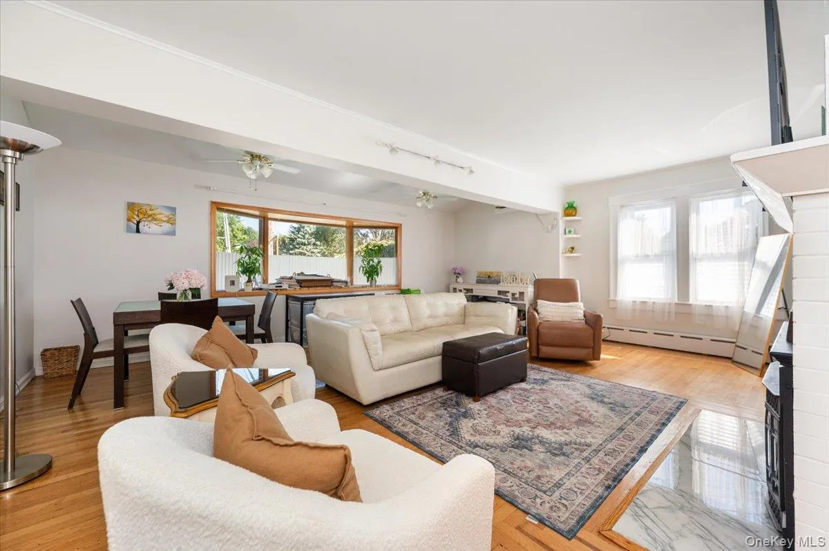 Living area with beam ceiling, healthy amount of natural light, baseboard heating, and light wood-type flooring Living area with beam ceiling, healthy amount of natural light, baseboard heating, and light wood-type flooring