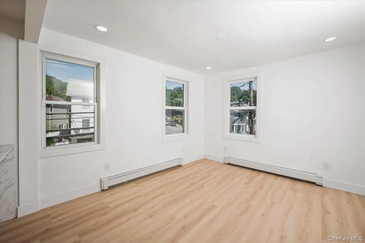 Unfurnished room featuring baseboard heating, a baseboard radiator, light wood finished floors, and recessed lighting Unfurnished room featuring baseboard heating, a baseboard radiator, light wood finished floors, and recessed lighting
