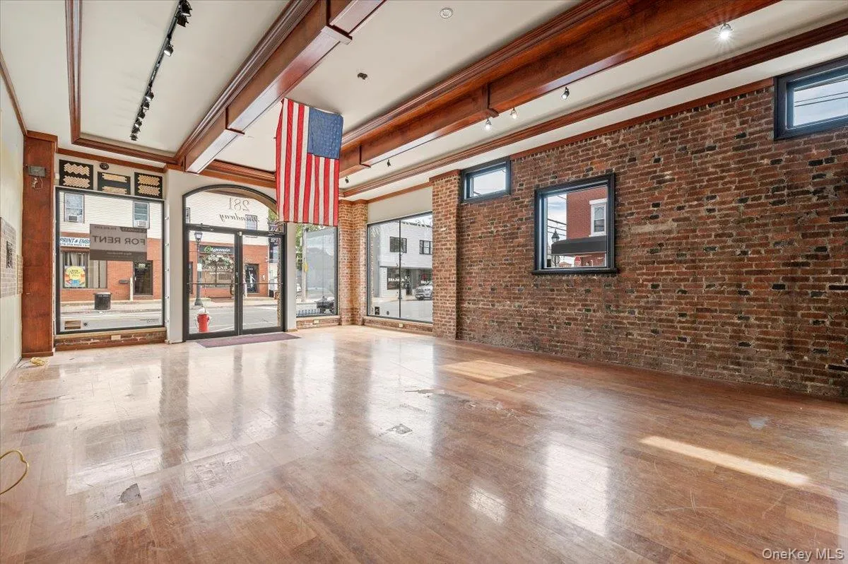 Common area featuring brick wall and beamed ceiling Common area featuring brick wall and beamed ceiling