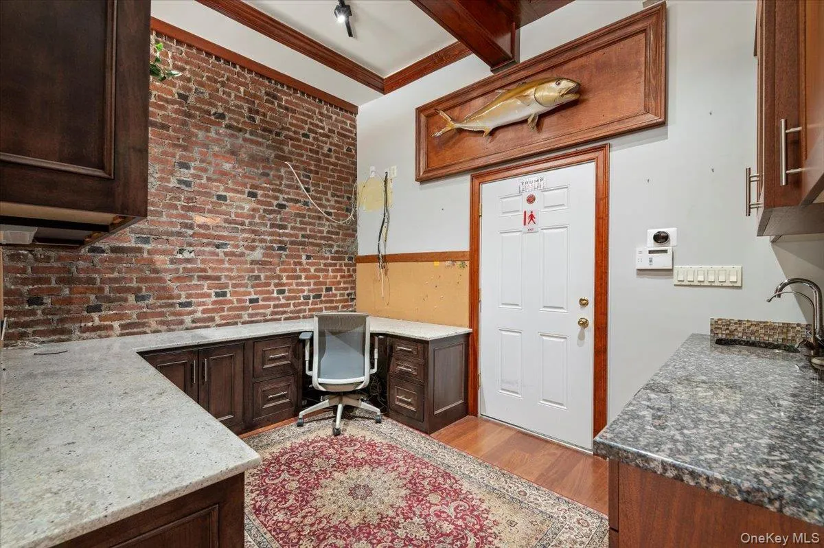 Office space featuring brick wall, light wood-style flooring, beamed ceiling, and crown molding Office space featuring brick wall, light wood-style flooring, beamed ceiling, and crown molding