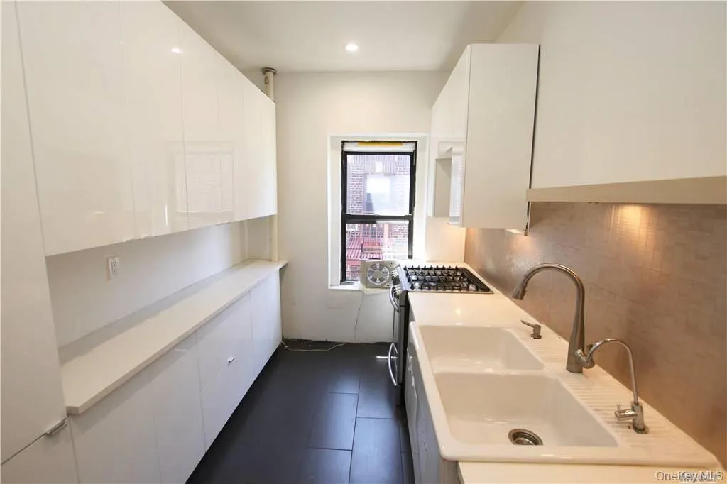 Kitchen featuring white cabinets, light countertops, stainless steel gas range oven, modern cabinets, and recessed lighting Kitchen featuring white cabinets, light countertops, stainless steel gas range oven, modern cabinets, and recessed lighting