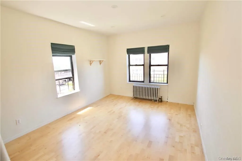 Unfurnished room with radiator and wood finished floors Unfurnished room with radiator and wood finished floors