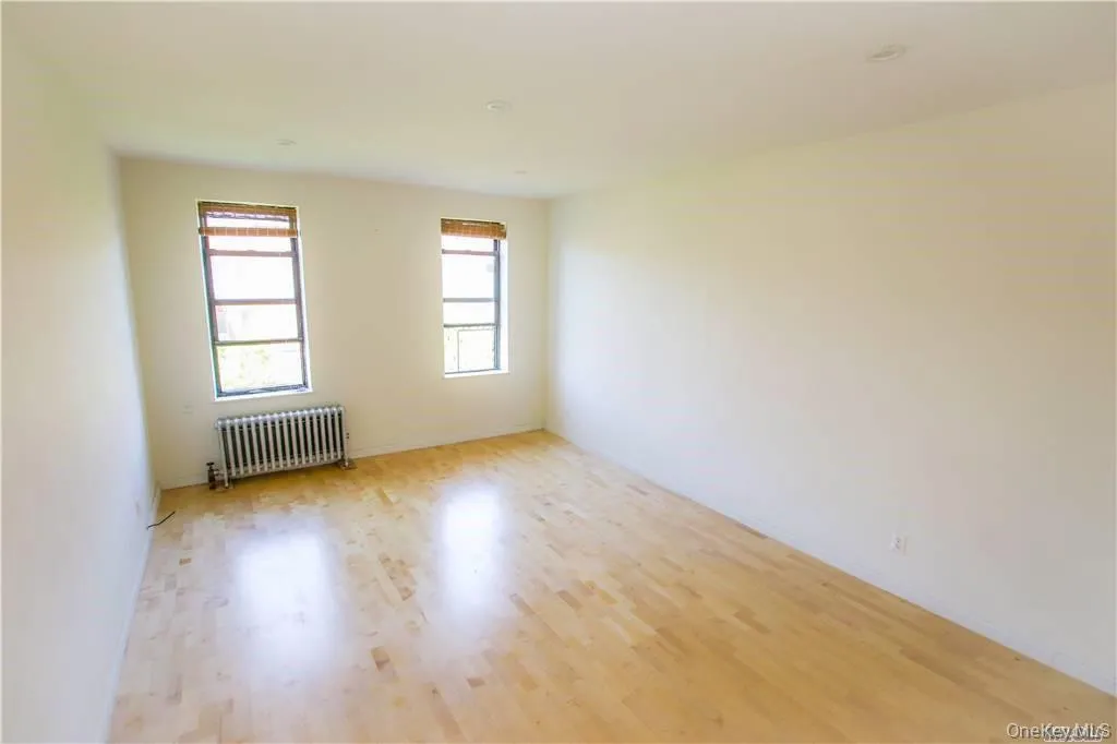 Unfurnished room with radiator and light wood finished floors Unfurnished room with radiator and light wood finished floors