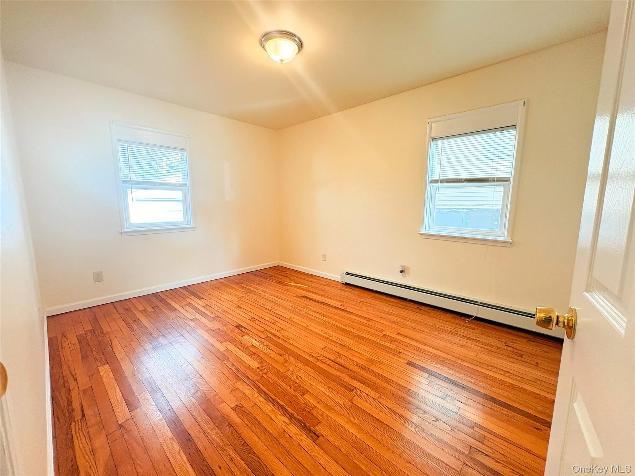 Empty room featuring a baseboard heating unit and light wood-type flooring Empty room featuring a baseboard heating unit and light wood-type flooring