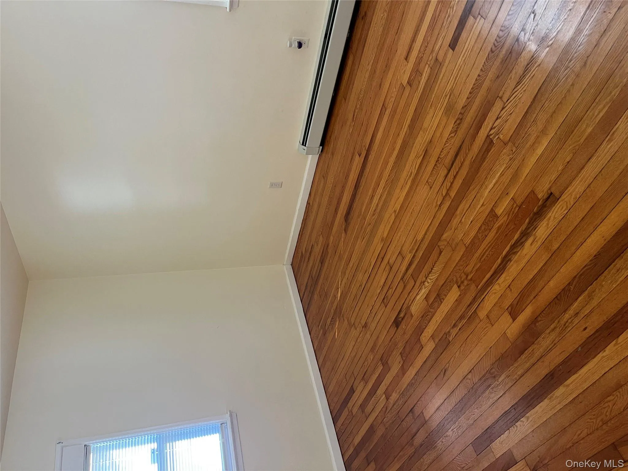 Unfurnished room with hardwood / wood-style flooring and baseboard heating Unfurnished room with hardwood / wood-style flooring and baseboard heating