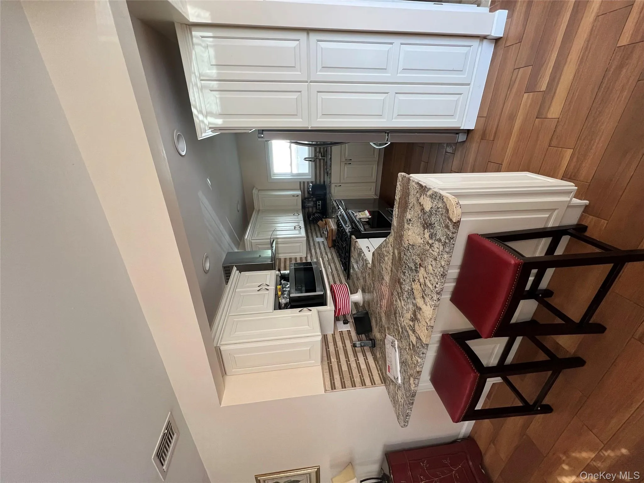Kitchen with backsplash, a peninsula, a breakfast bar area, dark wood-type flooring, and stainless steel range oven Kitchen with backsplash, a peninsula, a breakfast bar area, dark wood-type flooring, and stainless steel range oven