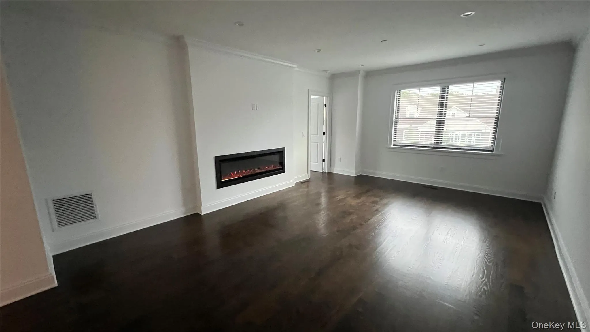 Unfurnished living room featuring dark wood-style floors, a glass covered fireplace, and recessed lighting Unfurnished living room featuring dark wood-style floors, a glass covered fireplace, and recessed lighting