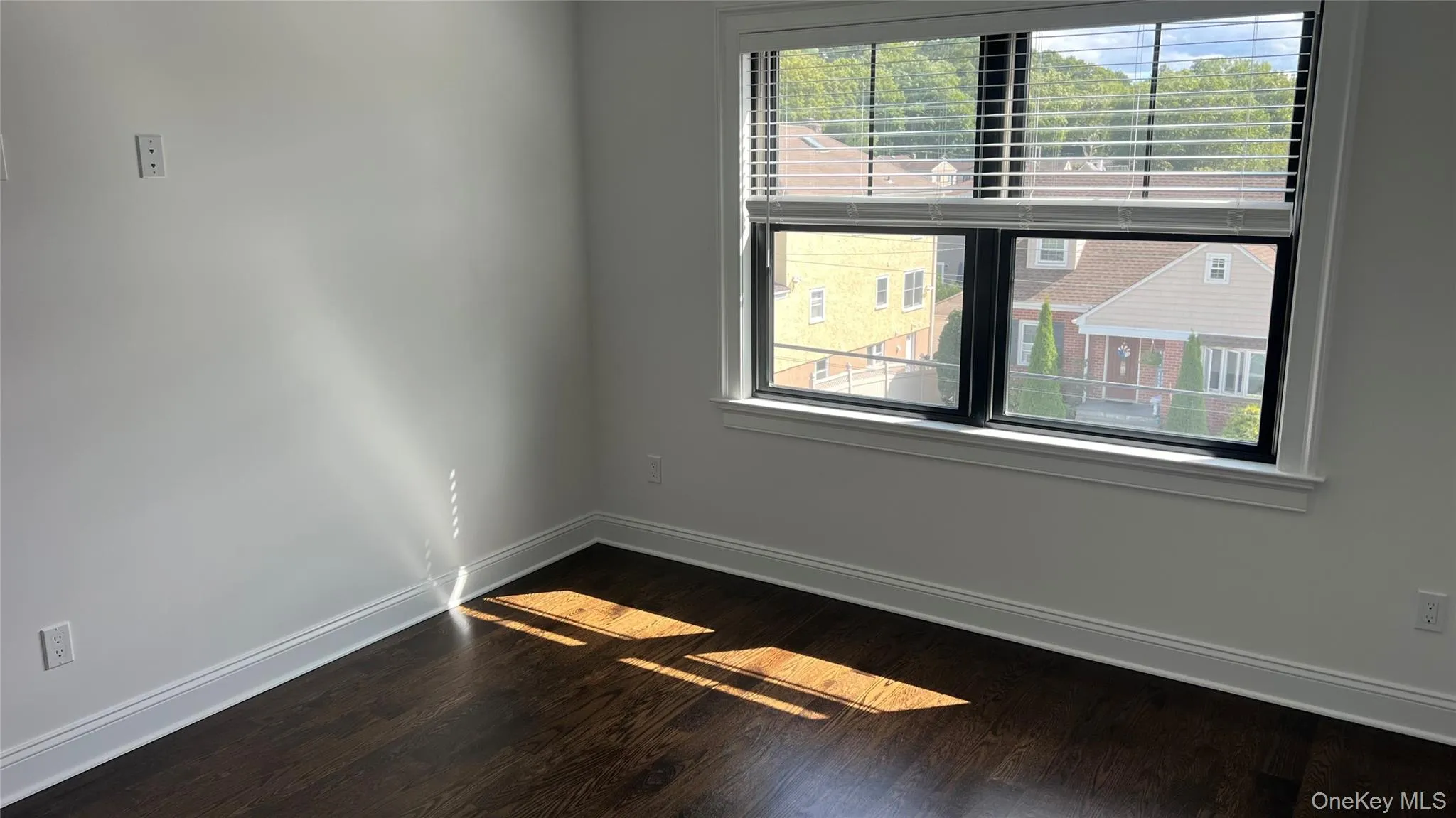 Unfurnished room featuring healthy amount of natural light and dark wood-style flooring Unfurnished room featuring healthy amount of natural light and dark wood-style flooring