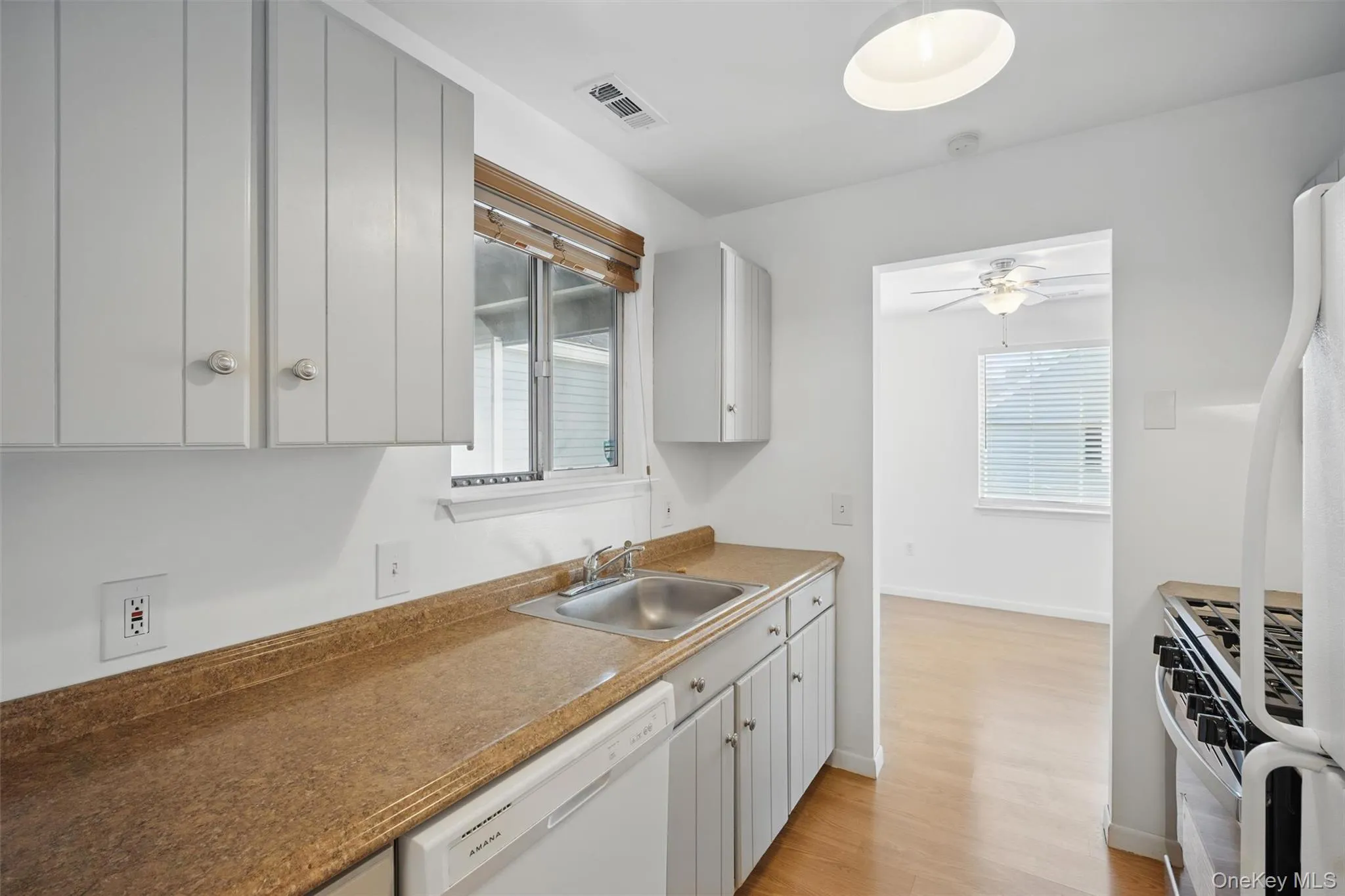 Kitchen with white appliances, light wood finished floors, and ceiling fan Kitchen with white appliances, light wood finished floors, and ceiling fan