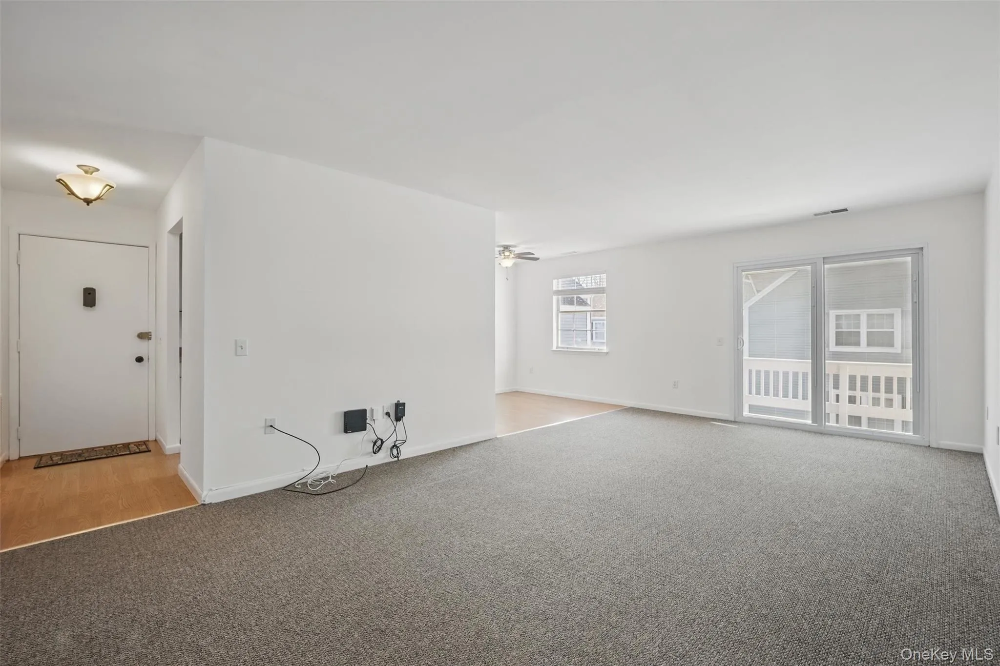 Unfurnished living room featuring light colored carpet and a ceiling fan Unfurnished living room featuring light colored carpet and a ceiling fan