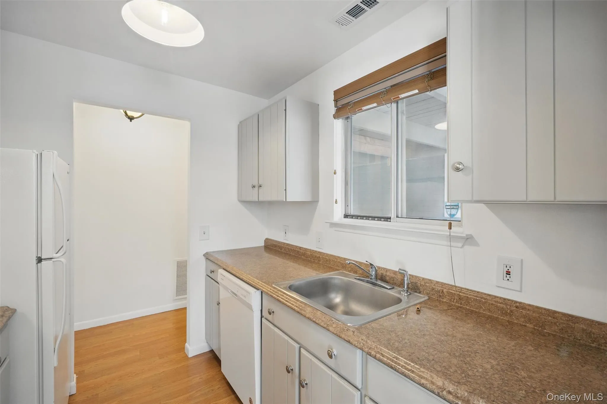 Kitchen featuring white appliances and light wood finished floors Kitchen featuring white appliances and light wood finished floors