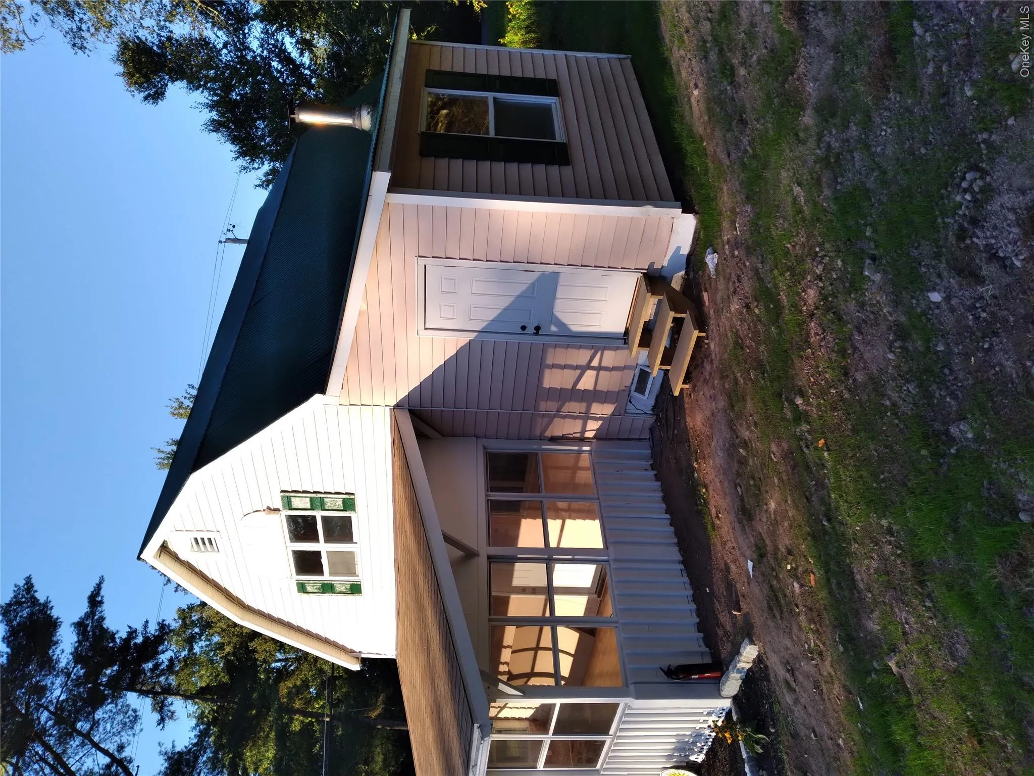 Back of property featuring a gambrel roof and a sunroom Back of property featuring a gambrel roof and a sunroom
