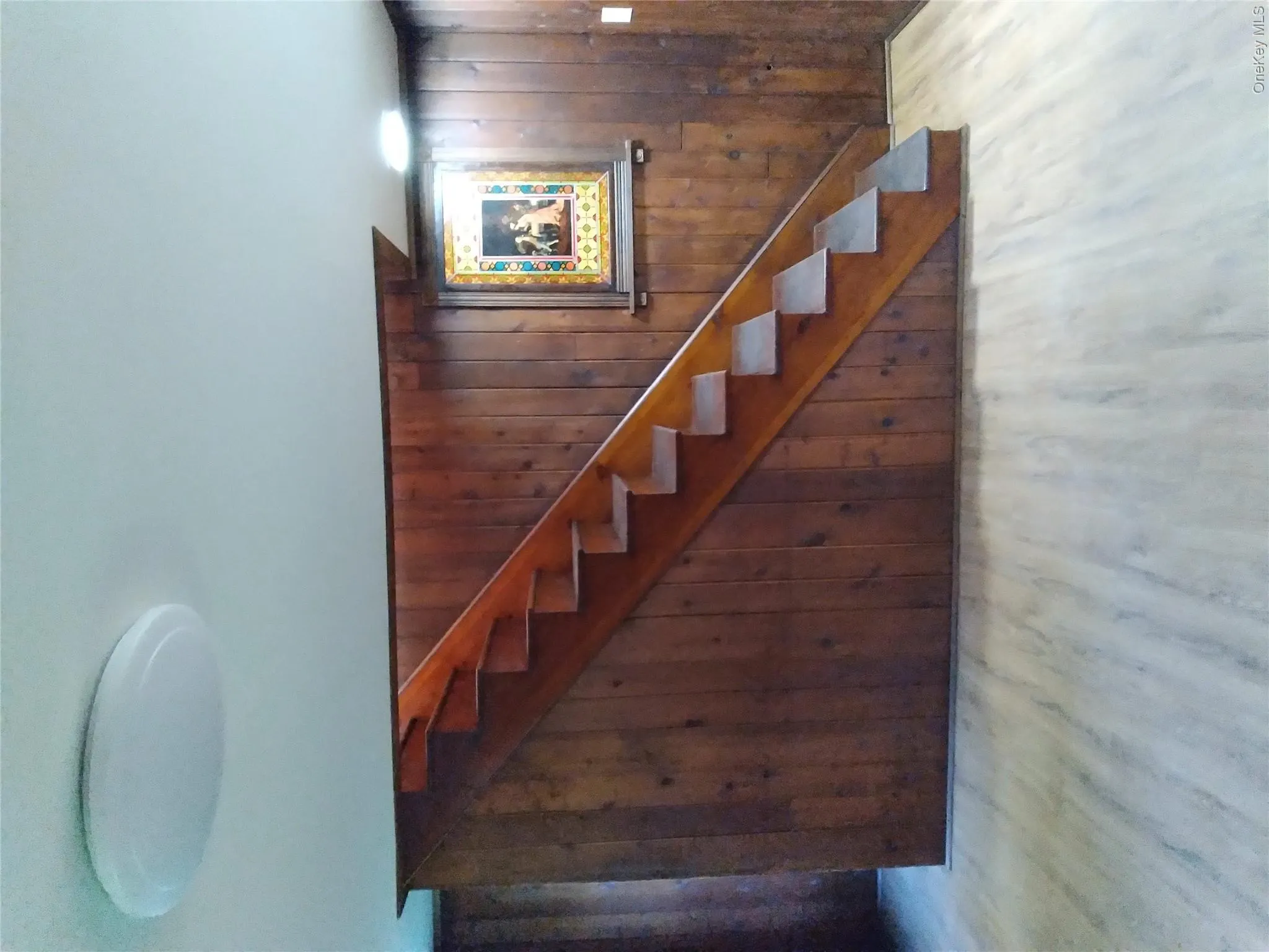 Staircase featuring wood walls and wood finished floors Staircase featuring wood walls and wood finished floors