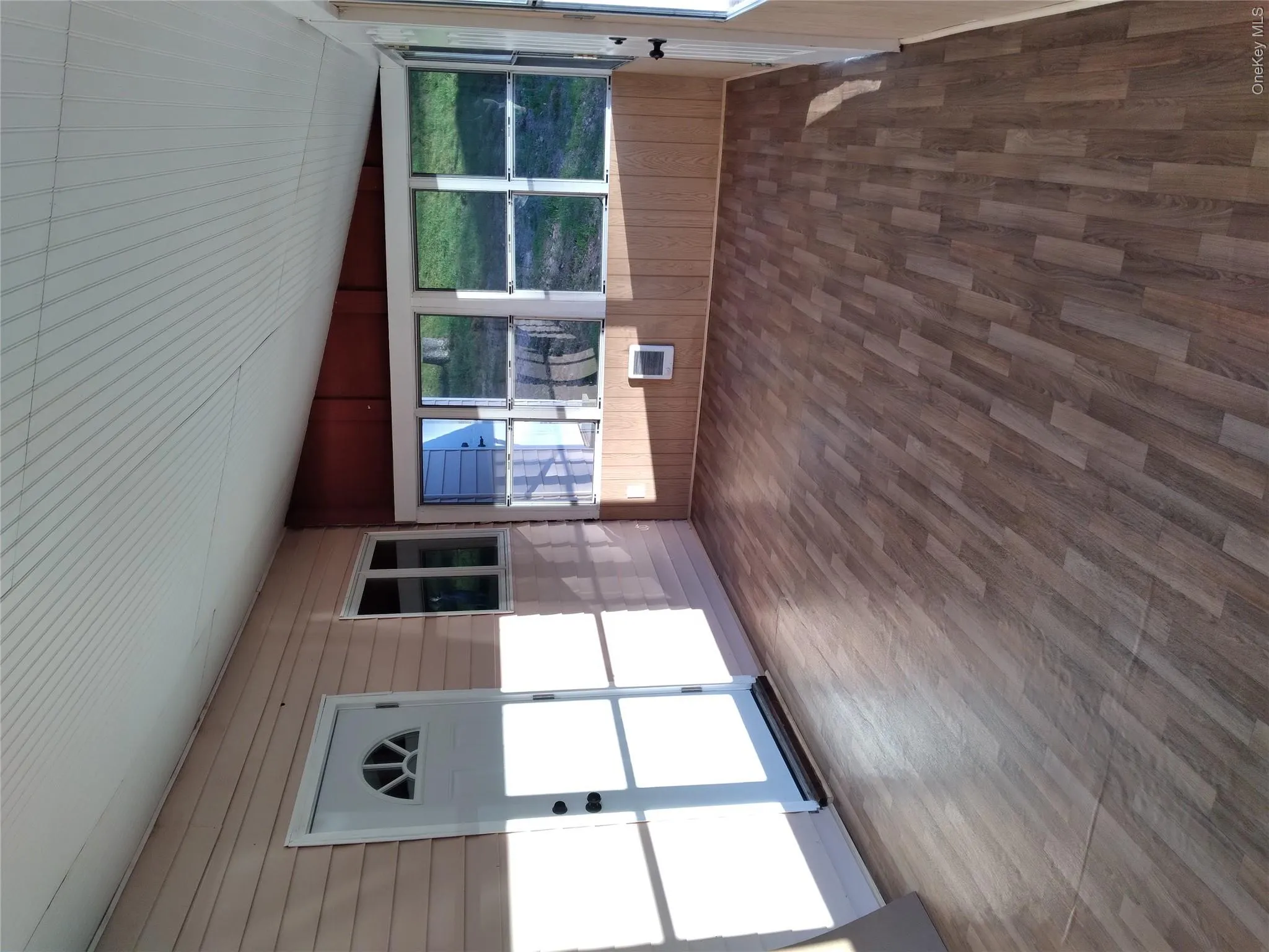 Unfurnished sunroom with wooden walls, lofted ceiling, and wood finished floors Unfurnished sunroom with wooden walls, lofted ceiling, and wood finished floors
