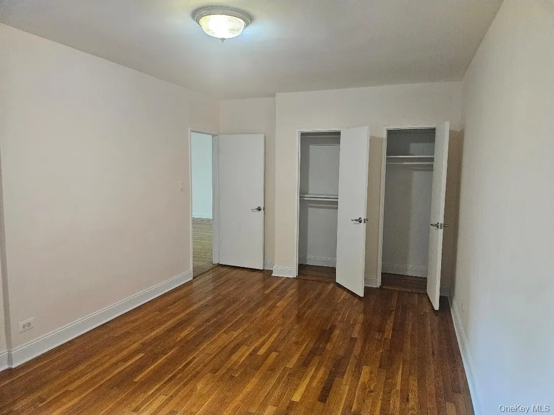 Unfurnished bedroom with two closets and dark wood-type flooring Unfurnished bedroom with two closets and dark wood-type flooring