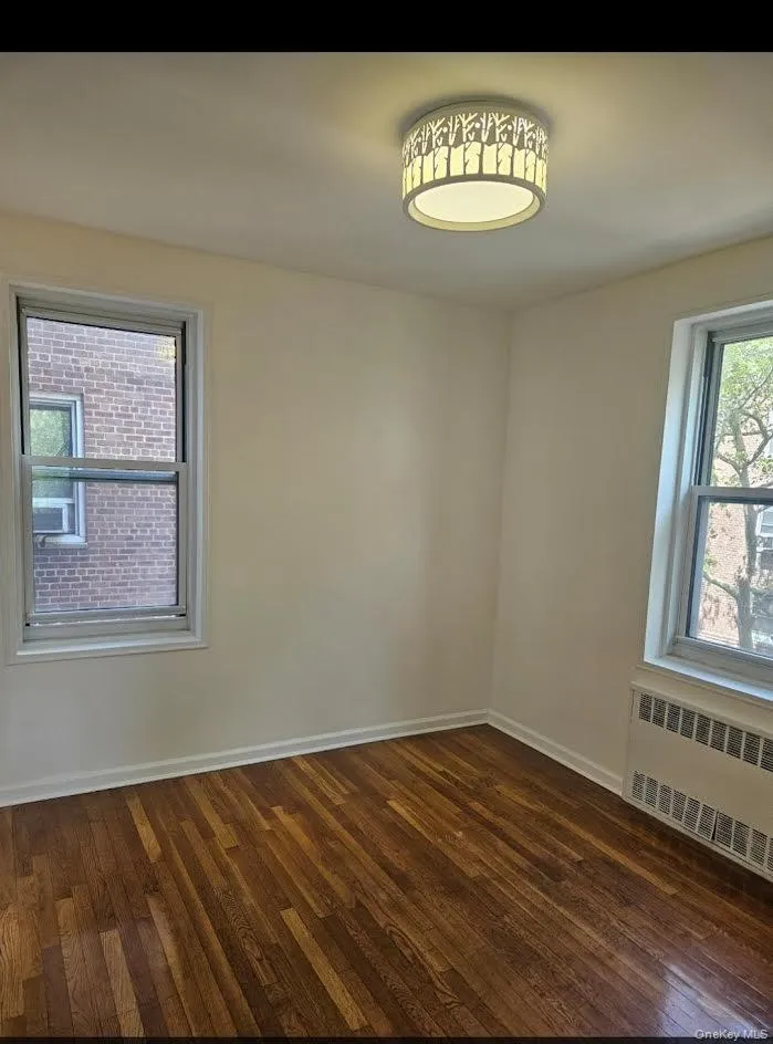 Spare room with radiator heating unit and dark wood-style flooring Spare room with radiator heating unit and dark wood-style flooring