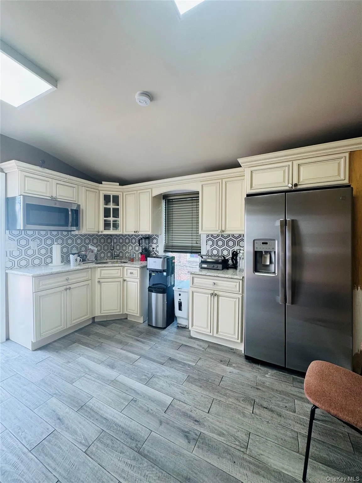Kitchen featuring decorative backsplash, stainless steel appliances, wood tiled floors, and glass insert cabinets Kitchen featuring decorative backsplash, stainless steel appliances, wood tiled floors, and glass insert cabinets