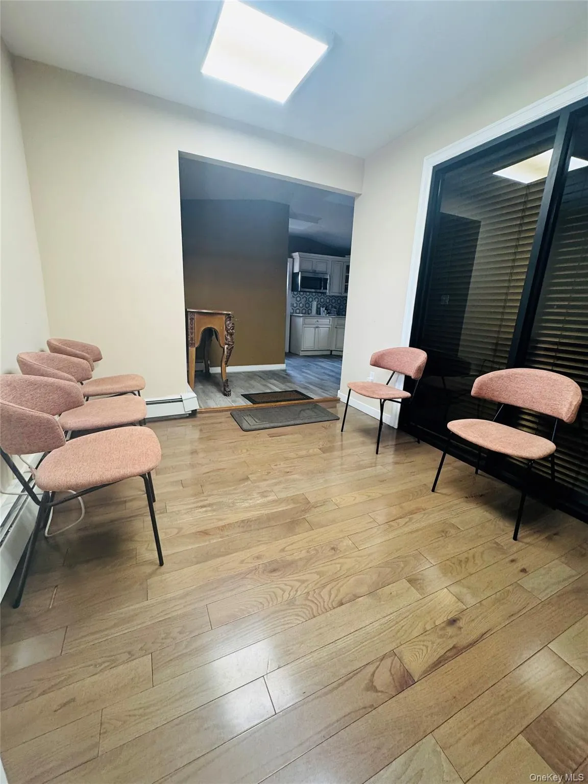 Living area with light wood finished floors and a baseboard heating unit Living area with light wood finished floors and a baseboard heating unit