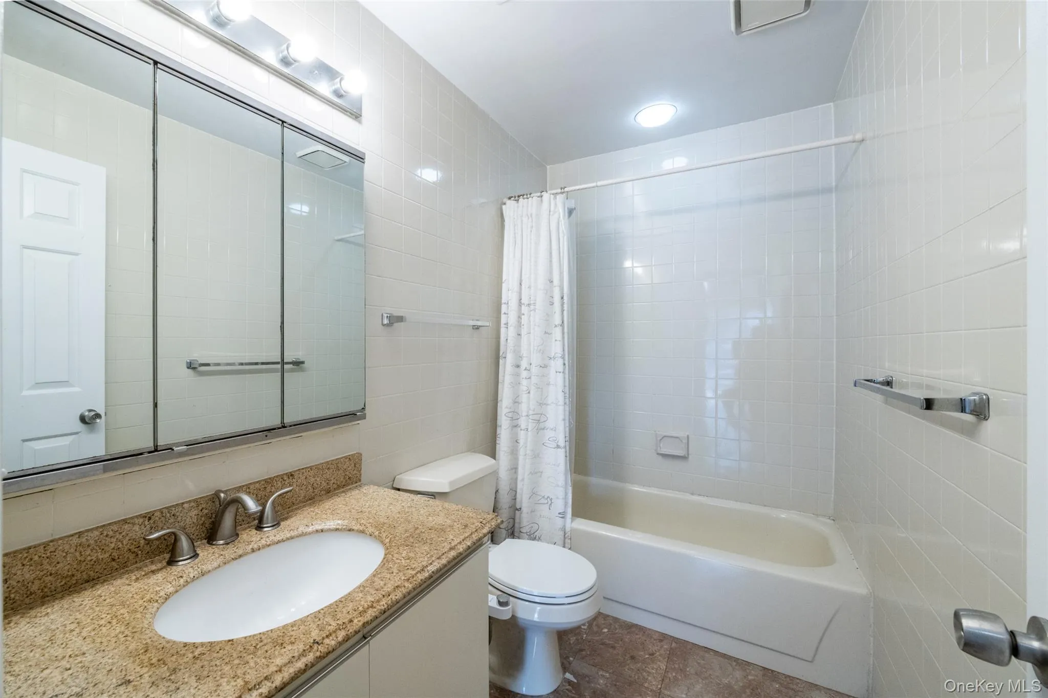 Full bath featuring shower / bath combo with shower curtain, vanity, and tile walls Full bath featuring shower / bath combo with shower curtain, vanity, and tile walls