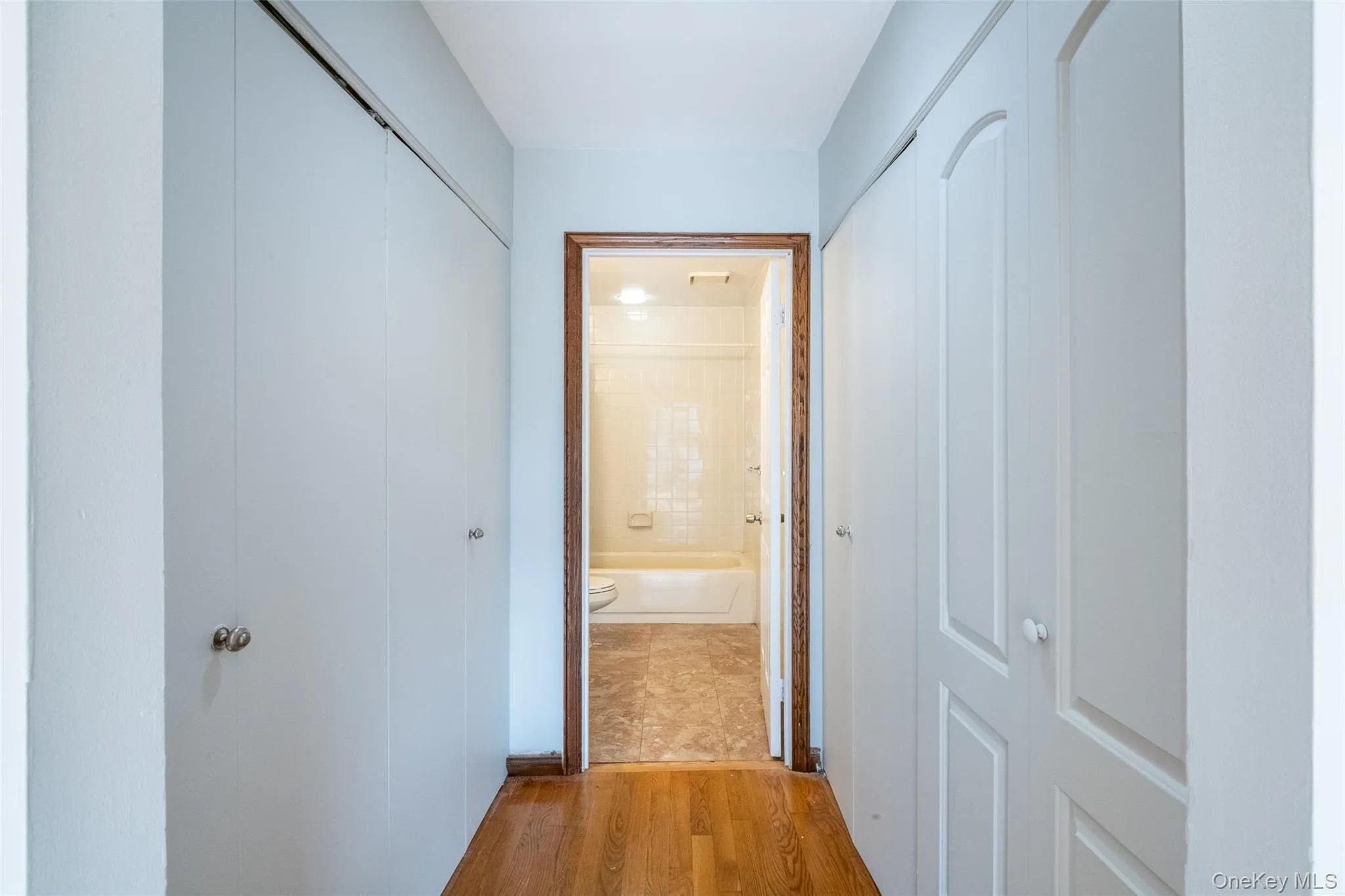 Hallway with wood finished floors, looking at the primary bathroom Hallway with wood finished floors, looking at the primary bathroom