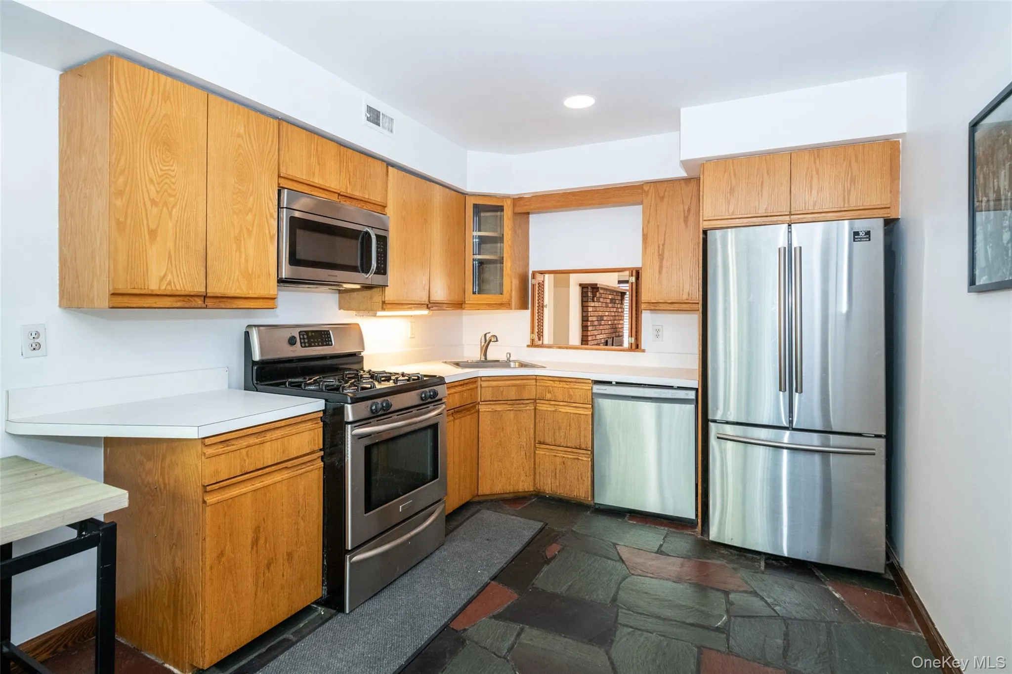 Kitchen with appliances with stainless steel finishes, light countertops, recessed lighting, stone tile flooring, Kitchen with appliances with stainless steel finishes, light countertops, recessed lighting, stone tile flooring,
