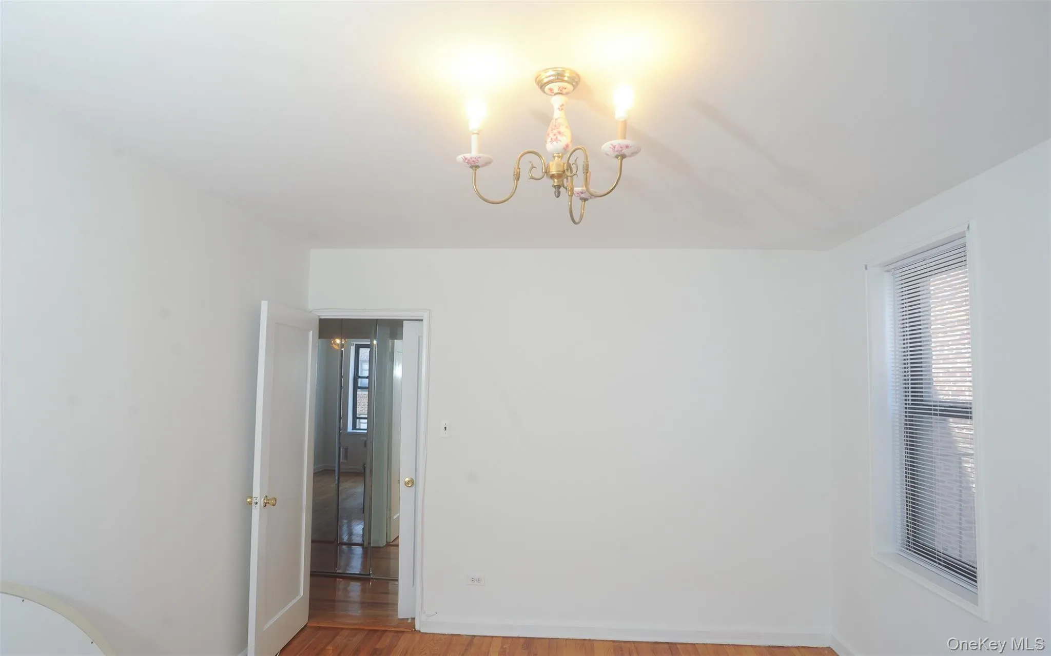Spare room with light wood finished floors, a chandelier, and plenty of natural light Spare room with light wood finished floors, a chandelier, and plenty of natural light