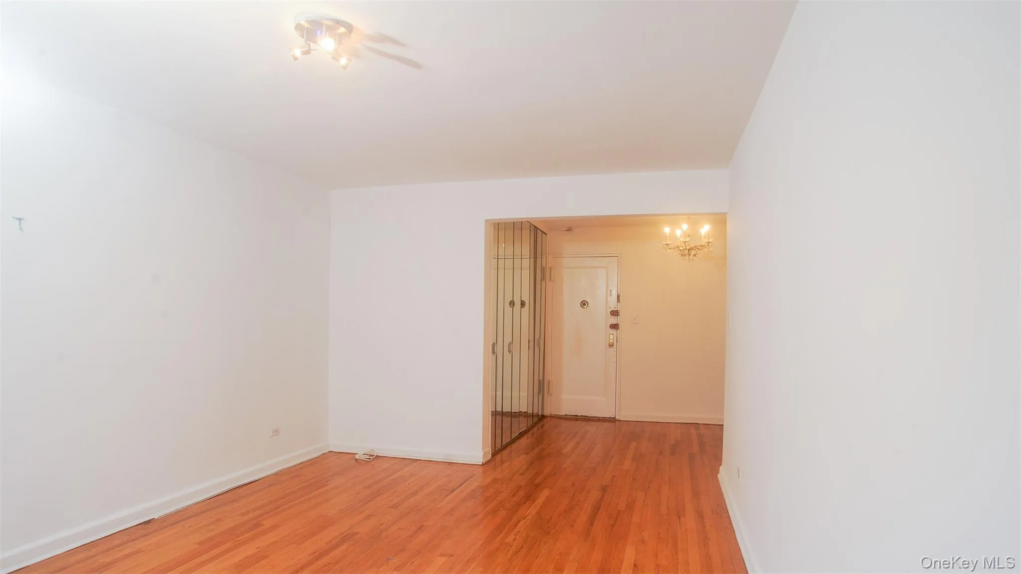 Spare room with light wood-type flooring and a chandelier Spare room with light wood-type flooring and a chandelier