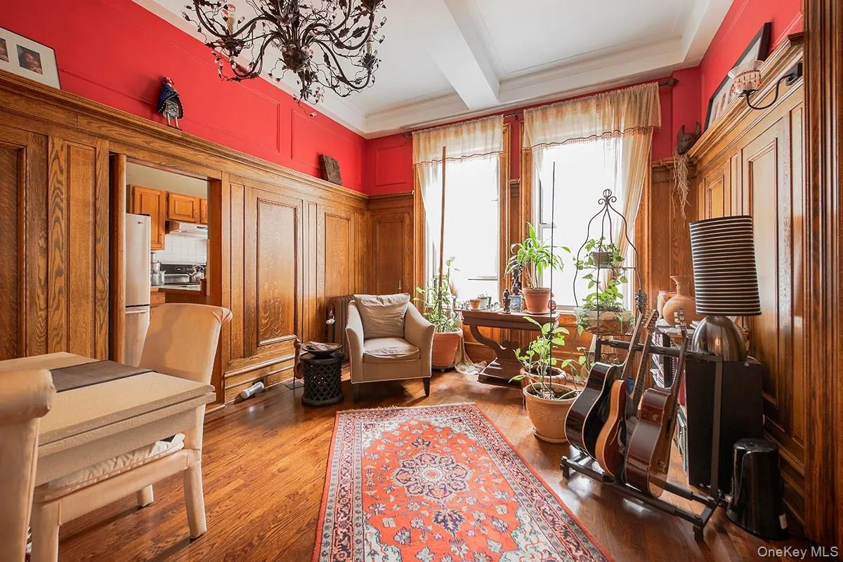 Living area with beamed ceiling, wood finished floors, coffered ceiling, ornamental molding, and a chandelier Living area with beamed ceiling, wood finished floors, coffered ceiling, ornamental molding, and a chandelier