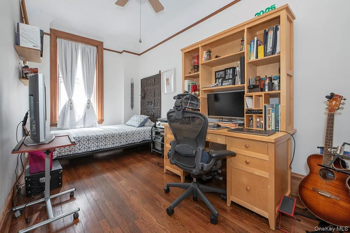 Bedroom with dark wood finished floors, a desk, a ceiling fan, and ornamental molding Bedroom with dark wood finished floors, a desk, a ceiling fan, and ornamental molding