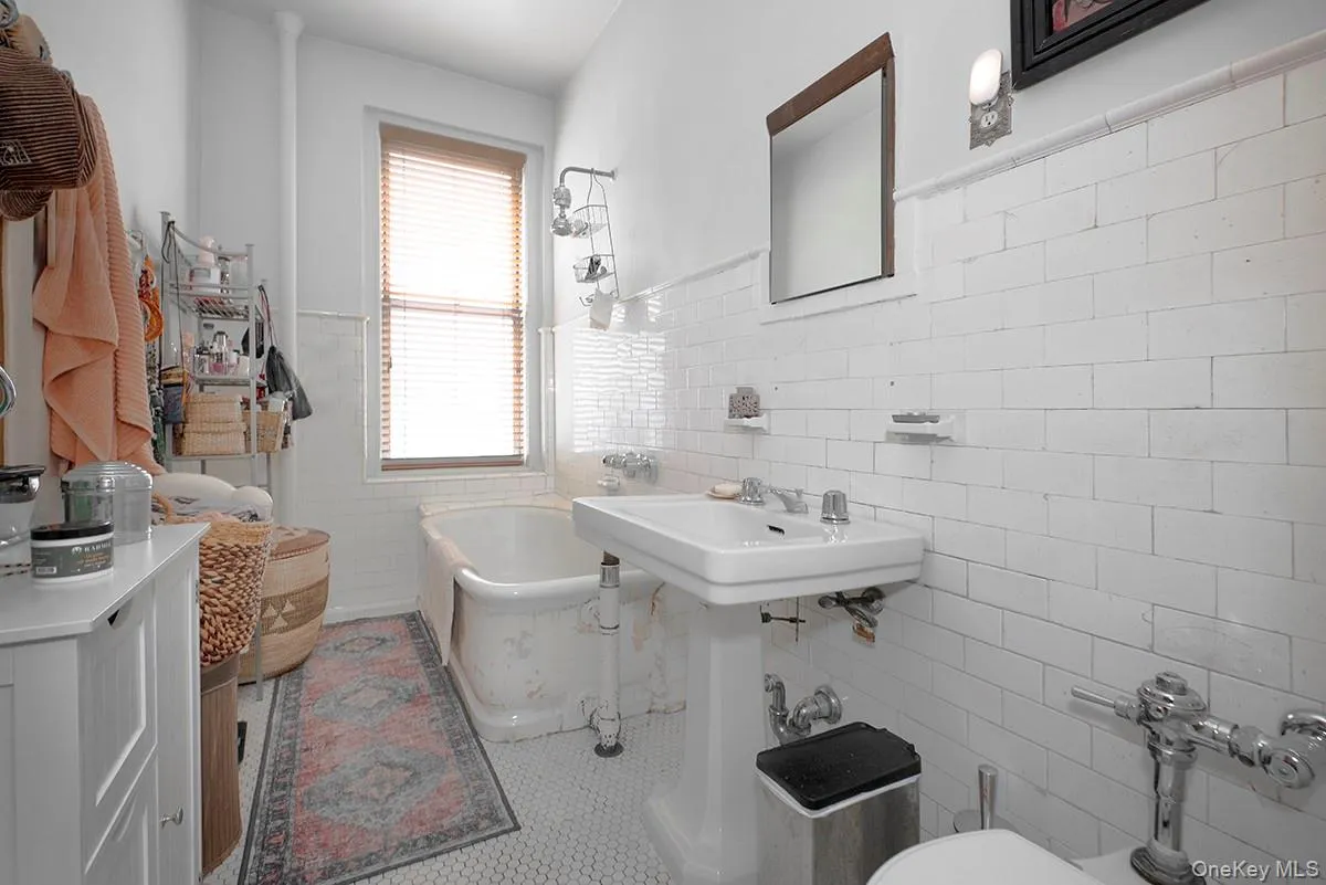 Full bathroom featuring tile walls, wainscoting, tile patterned floors, and shower / tub combination Full bathroom featuring tile walls, wainscoting, tile patterned floors, and shower / tub combination