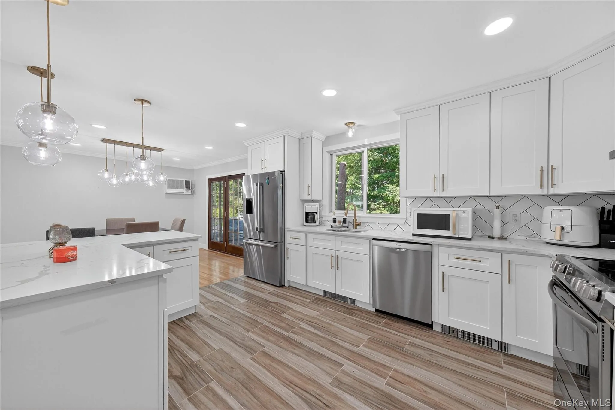 Kitchen featuring decorative backsplash, recessed lighting, appliances with stainless steel finishes, white cabinets, and light stone counters Kitchen featuring decorative backsplash, recessed lighting, appliances with stainless steel finishes, white cabinets, and light stone counters