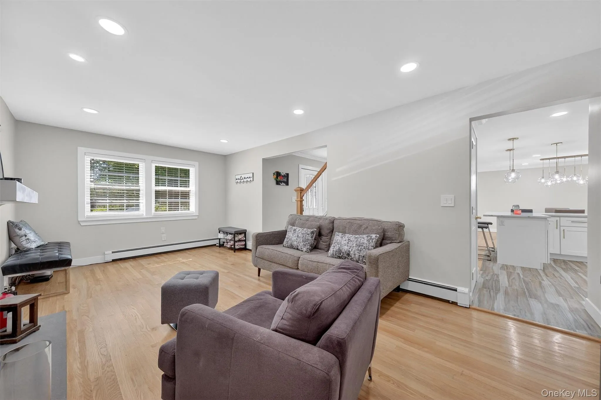 Living area with light wood-type flooring, a baseboard radiator, recessed lighting, and stairs Living area with light wood-type flooring, a baseboard radiator, recessed lighting, and stairs