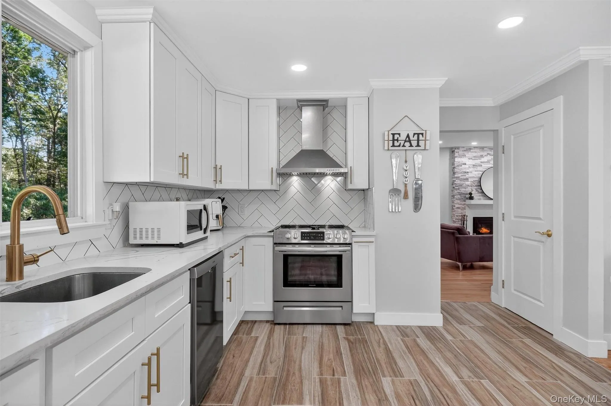 Kitchen with a fireplace, decorative backsplash, white cabinets, light stone countertops, and recessed lighting Kitchen with a fireplace, decorative backsplash, white cabinets, light stone countertops, and recessed lighting