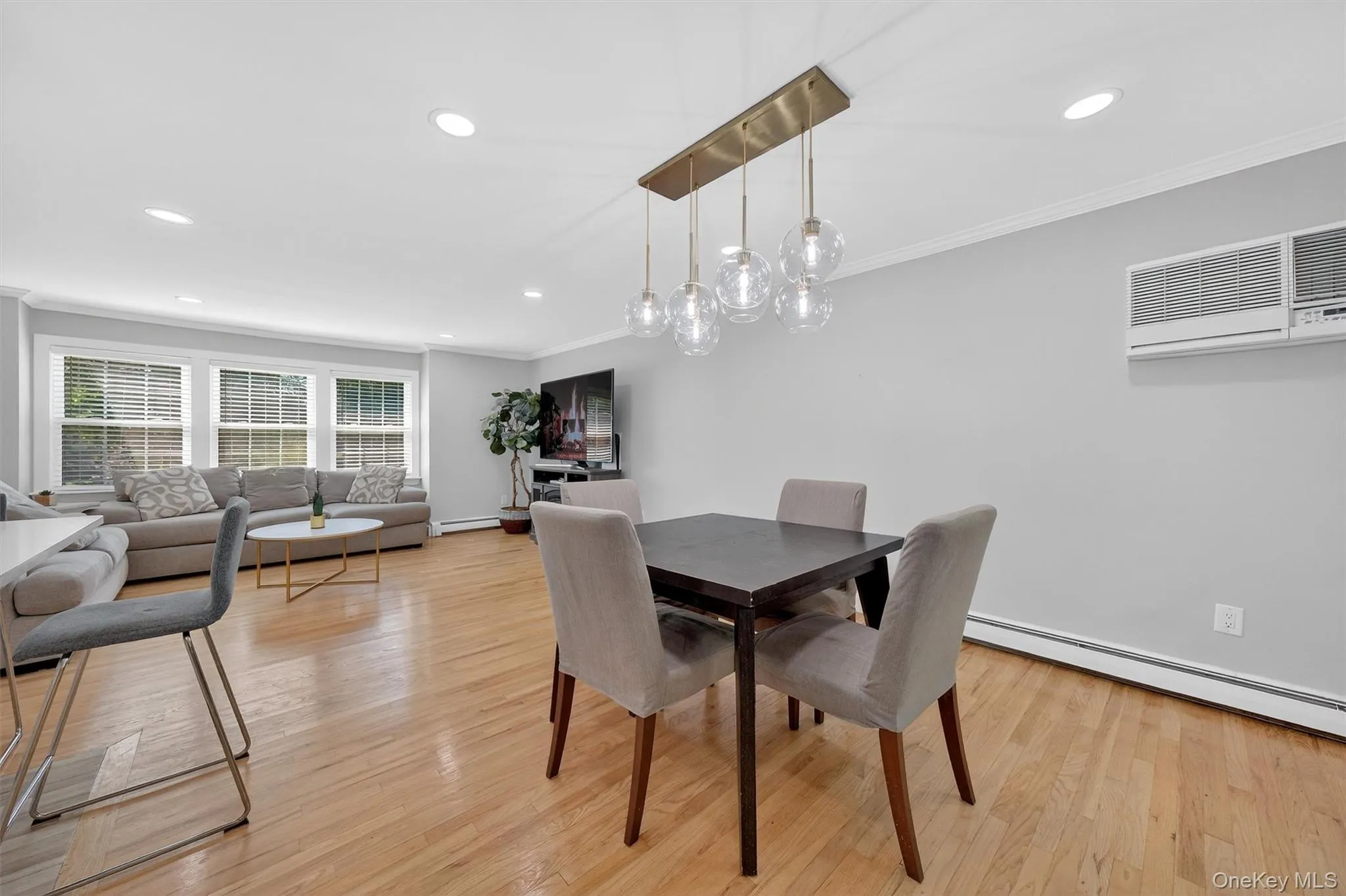 Dining space with light wood-style floors, baseboard heating, recessed lighting, ornamental molding, and a wall mounted air conditioner Dining space with light wood-style floors, baseboard heating, recessed lighting, ornamental molding, and a wall mounted air conditioner