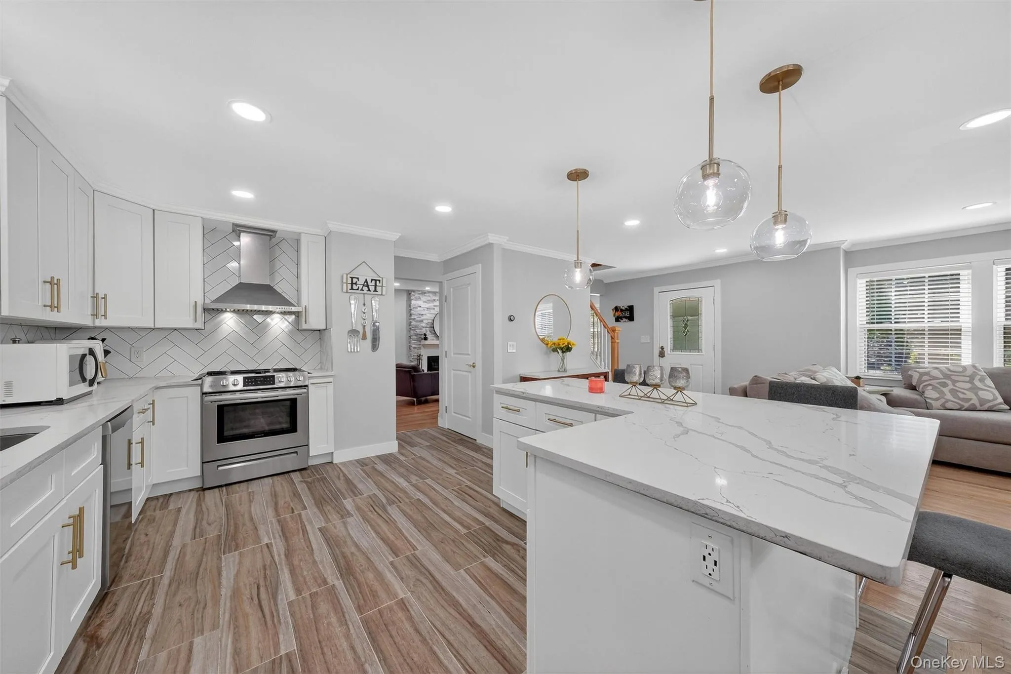 Kitchen featuring light stone countertops, white cabinetry, appliances with stainless steel finishes, light wood-type flooring, and recessed lighting Kitchen featuring light stone countertops, white cabinetry, appliances with stainless steel finishes, light wood-type flooring, and recessed lighting