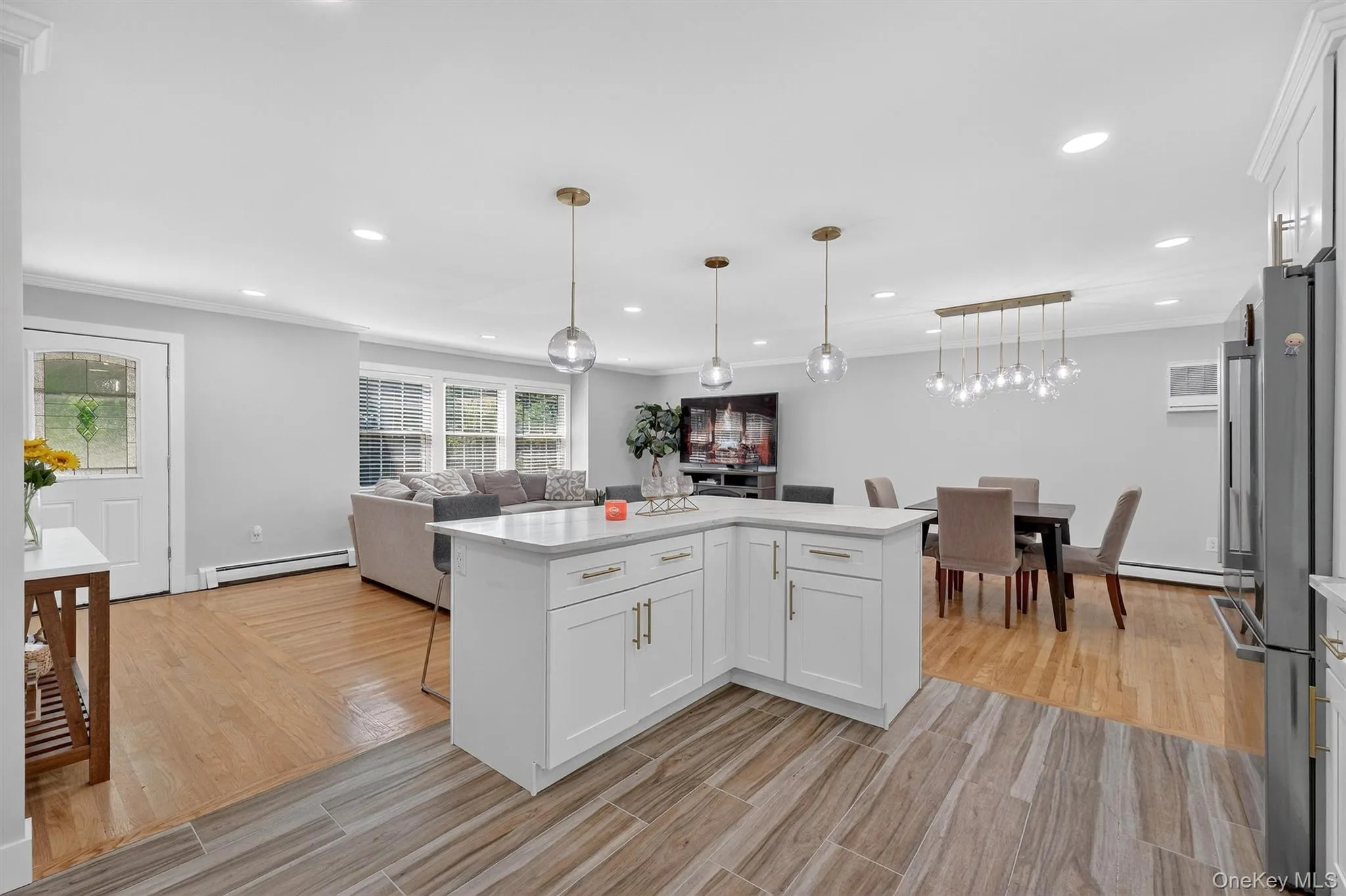 Kitchen with white cabinetry, open floor plan, decorative light fixtures, light wood finished floors, and recessed lighting Kitchen with white cabinetry, open floor plan, decorative light fixtures, light wood finished floors, and recessed lighting