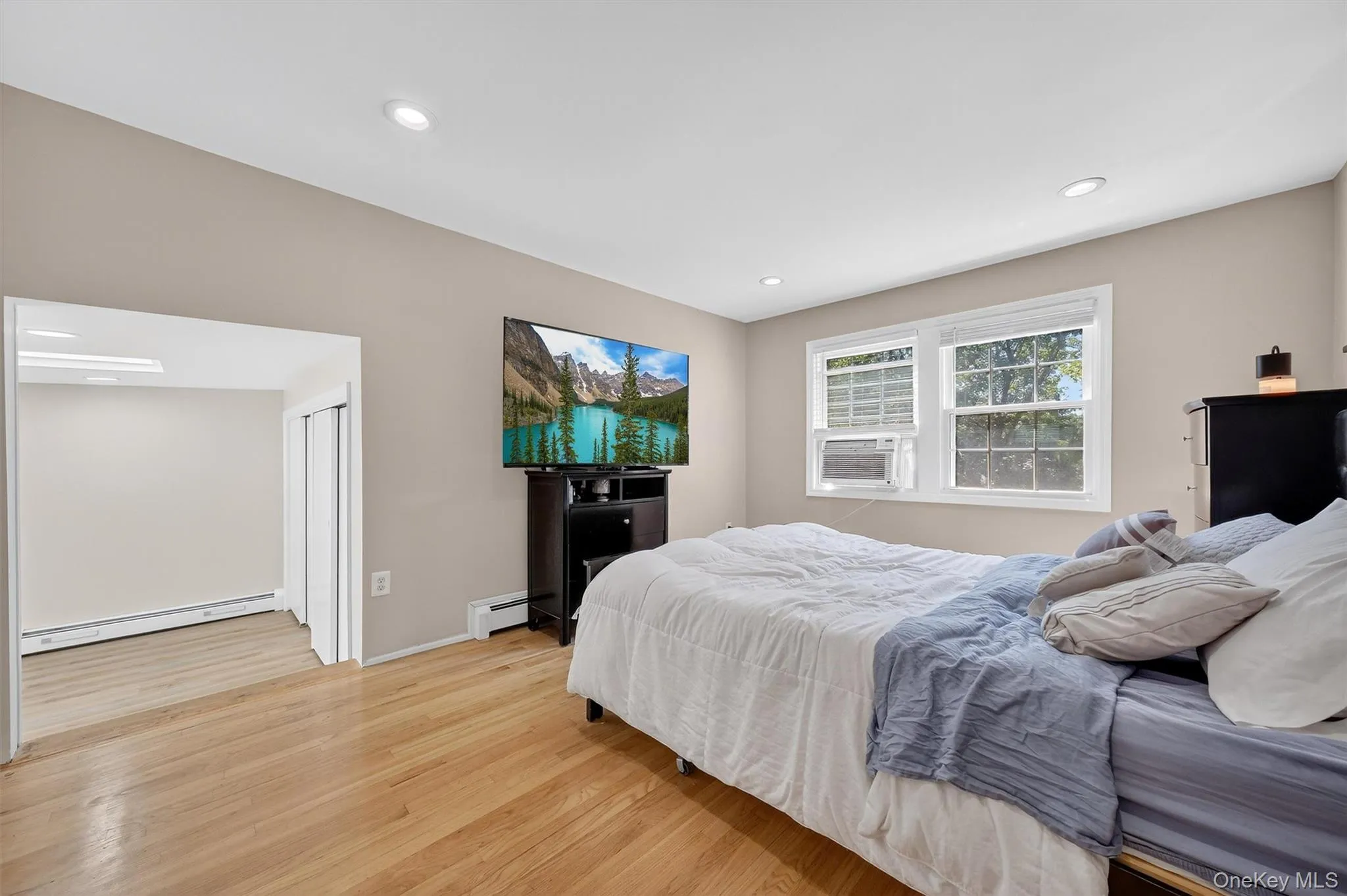 Bedroom with wood finished floors, baseboard heating, recessed lighting, and cooling unit Bedroom with wood finished floors, baseboard heating, recessed lighting, and cooling unit