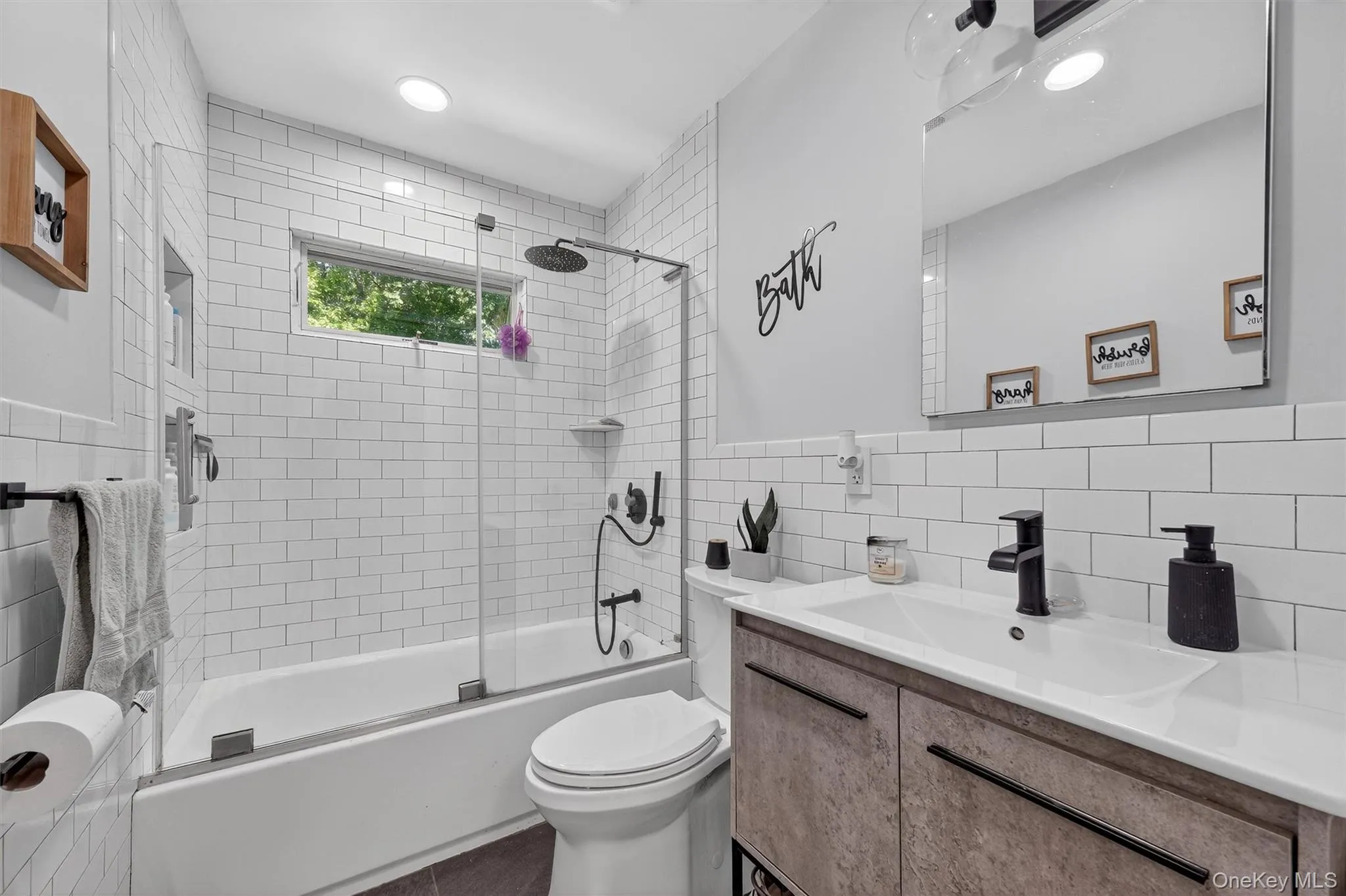 Full bathroom with combined bath / shower with glass door, vanity, tile walls, and backsplash Full bathroom with combined bath / shower with glass door, vanity, tile walls, and backsplash