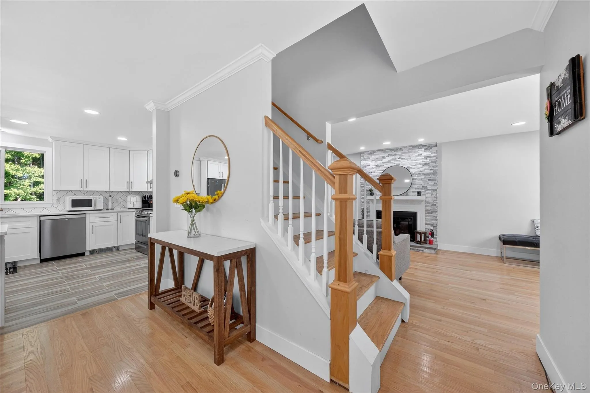 Stairway with wood finished floors, ornamental molding, a fireplace, and recessed lighting Stairway with wood finished floors, ornamental molding, a fireplace, and recessed lighting