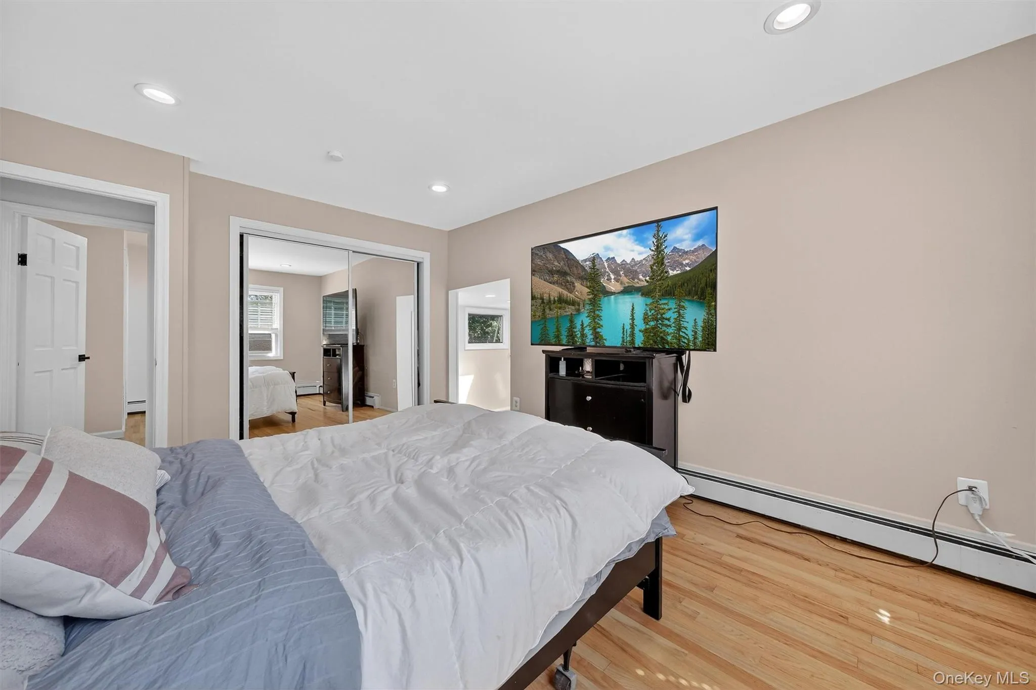 Bedroom featuring wood finished floors, recessed lighting, a closet, and a baseboard radiator Bedroom featuring wood finished floors, recessed lighting, a closet, and a baseboard radiator