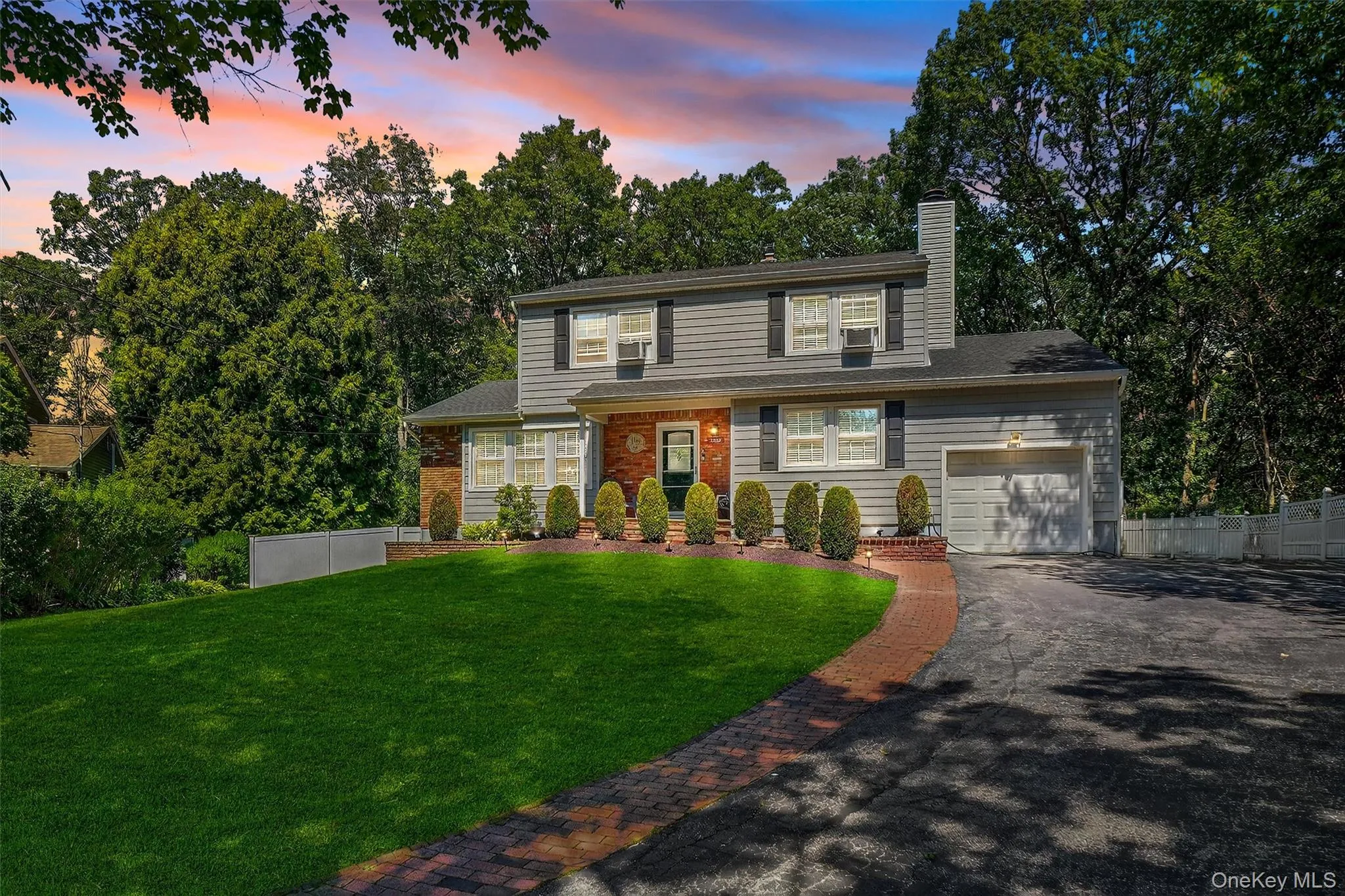 Traditional home with driveway, a chimney, brick siding, and an attached garage Traditional home with driveway, a chimney, brick siding, and an attached garage