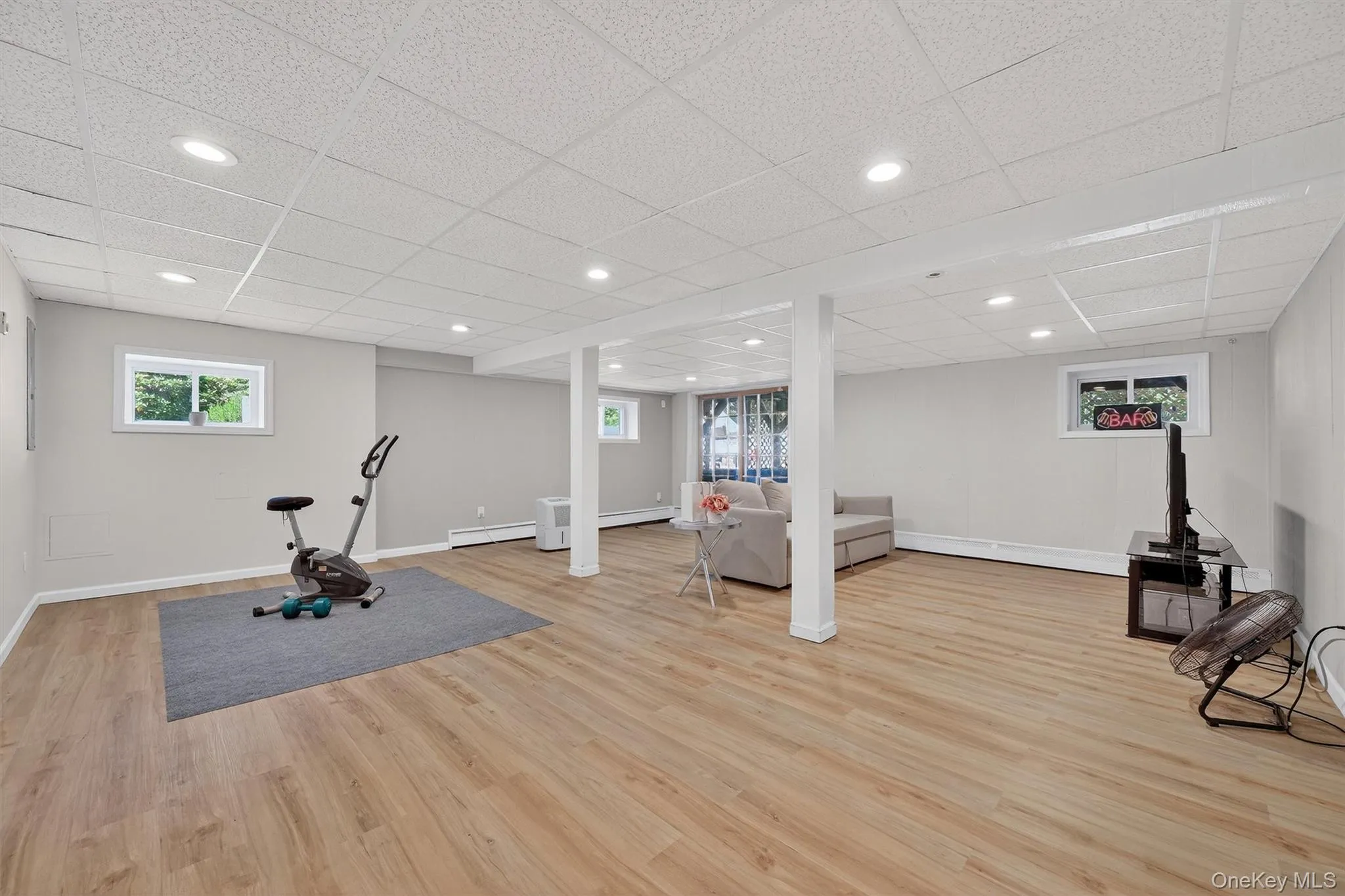 Lower Level - Workout area with plenty of natural light, a drop ceiling, recessed lighting, light wood-style flooring, and baseboard heating Lower Level - Workout area with plenty of natural light, a drop ceiling, recessed lighting, light wood-style flooring, and baseboard heating