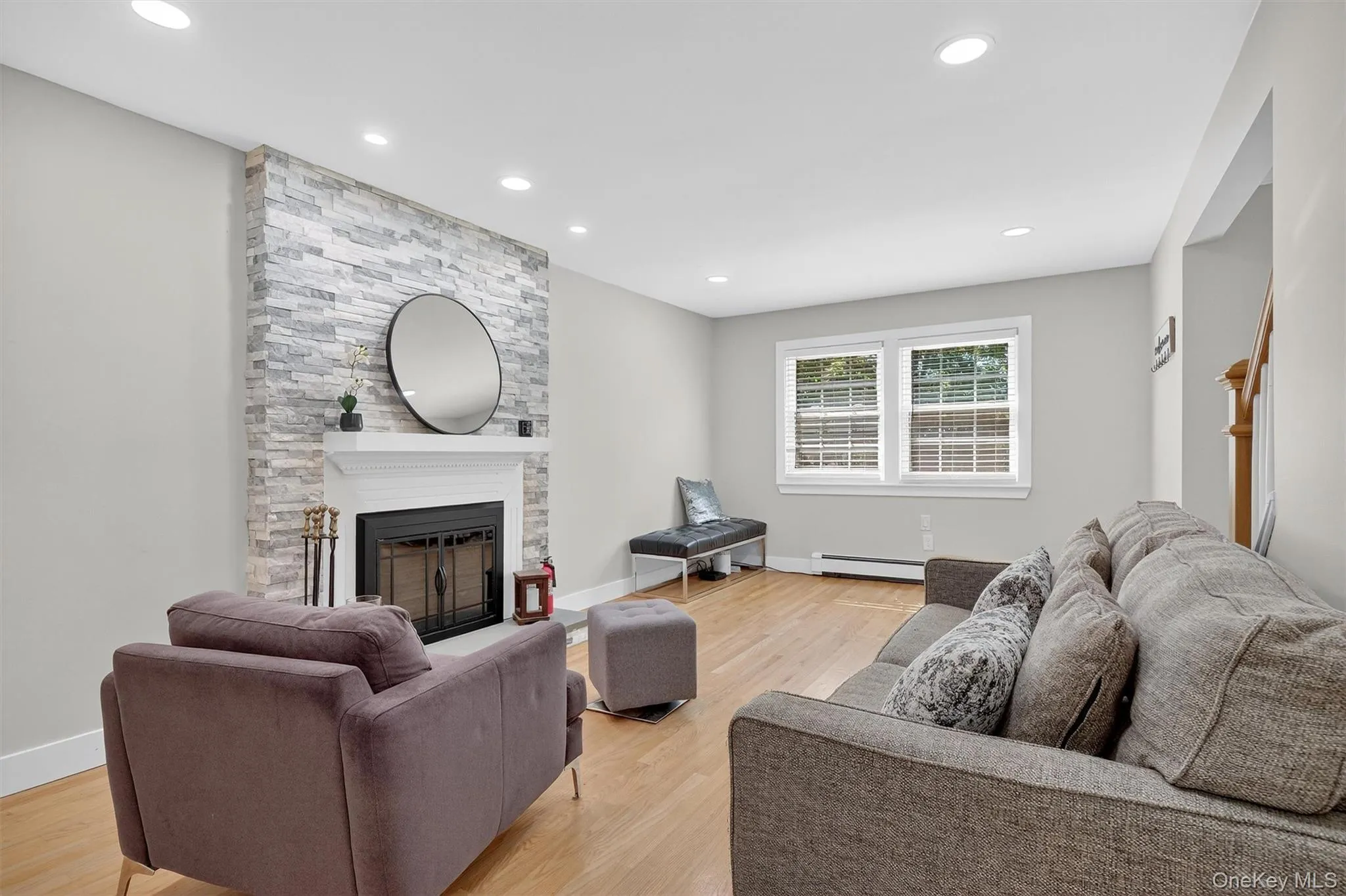 Living area featuring a fireplace, light wood-style flooring, recessed lighting, and baseboard heating Living area featuring a fireplace, light wood-style flooring, recessed lighting, and baseboard heating