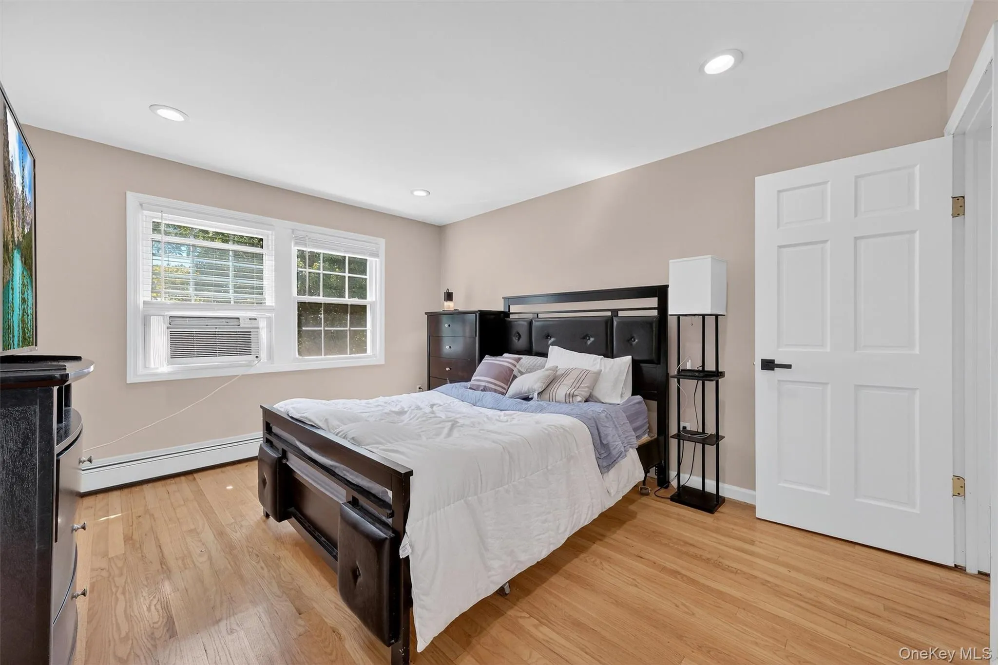 Bedroom featuring light wood-type flooring, a baseboard heating unit, recessed lighting, and cooling unit Bedroom featuring light wood-type flooring, a baseboard heating unit, recessed lighting, and cooling unit