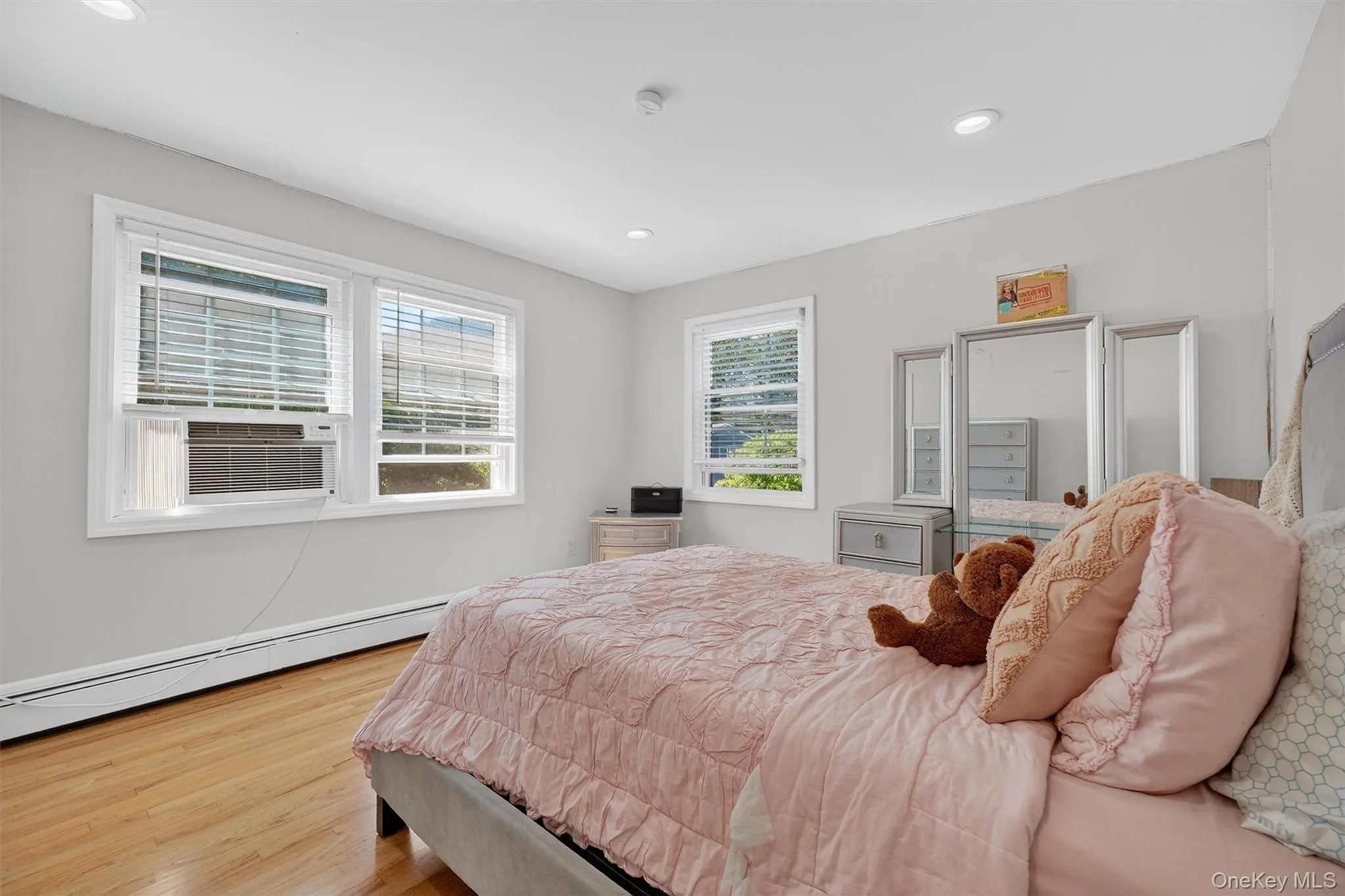 Bedroom featuring light wood-style floors, recessed lighting, a baseboard radiator, and cooling unit Bedroom featuring light wood-style floors, recessed lighting, a baseboard radiator, and cooling unit
