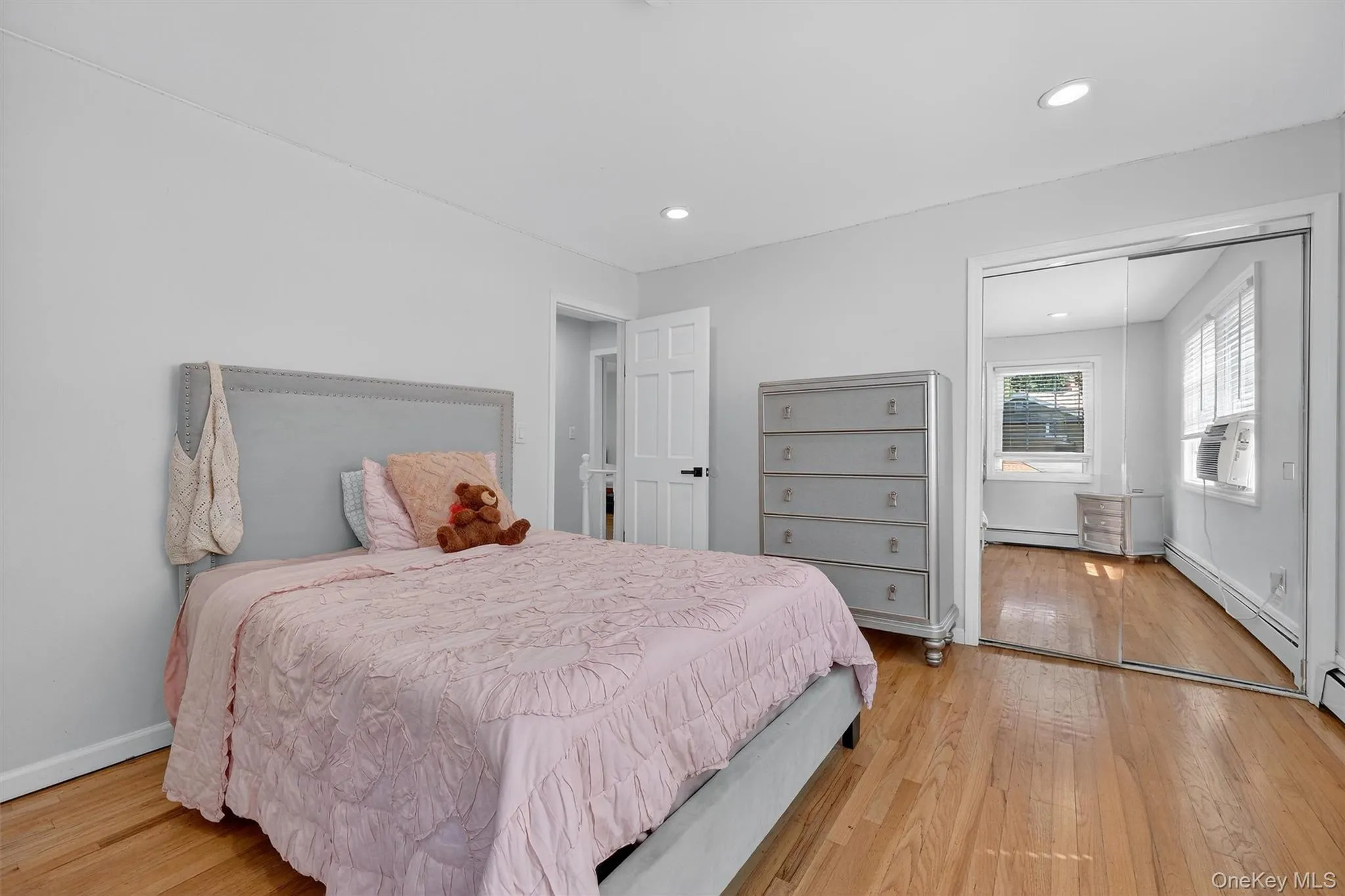 Bedroom featuring light wood-style floors, a closet, recessed lighting, and a baseboard heating unit Bedroom featuring light wood-style floors, a closet, recessed lighting, and a baseboard heating unit
