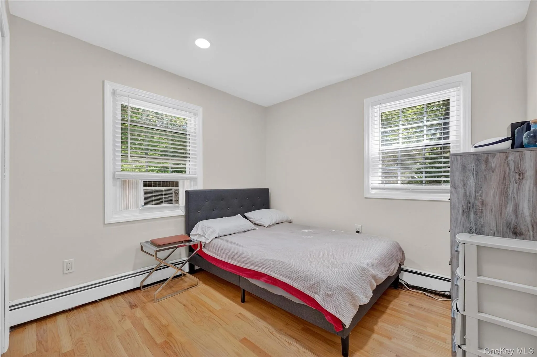 Bedroom with baseboard heating, light wood-style floors, recessed lighting, and cooling unit Bedroom with baseboard heating, light wood-style floors, recessed lighting, and cooling unit