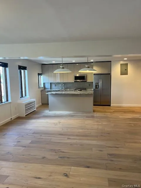 Kitchen featuring decorative backsplash, stainless steel appliances, a kitchen island, light wood-style floors, and recessed lighting Kitchen featuring decorative backsplash, stainless steel appliances, a kitchen island, light wood-style floors, and recessed lighting